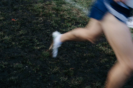 Runner's legs in motion on grassy terrain