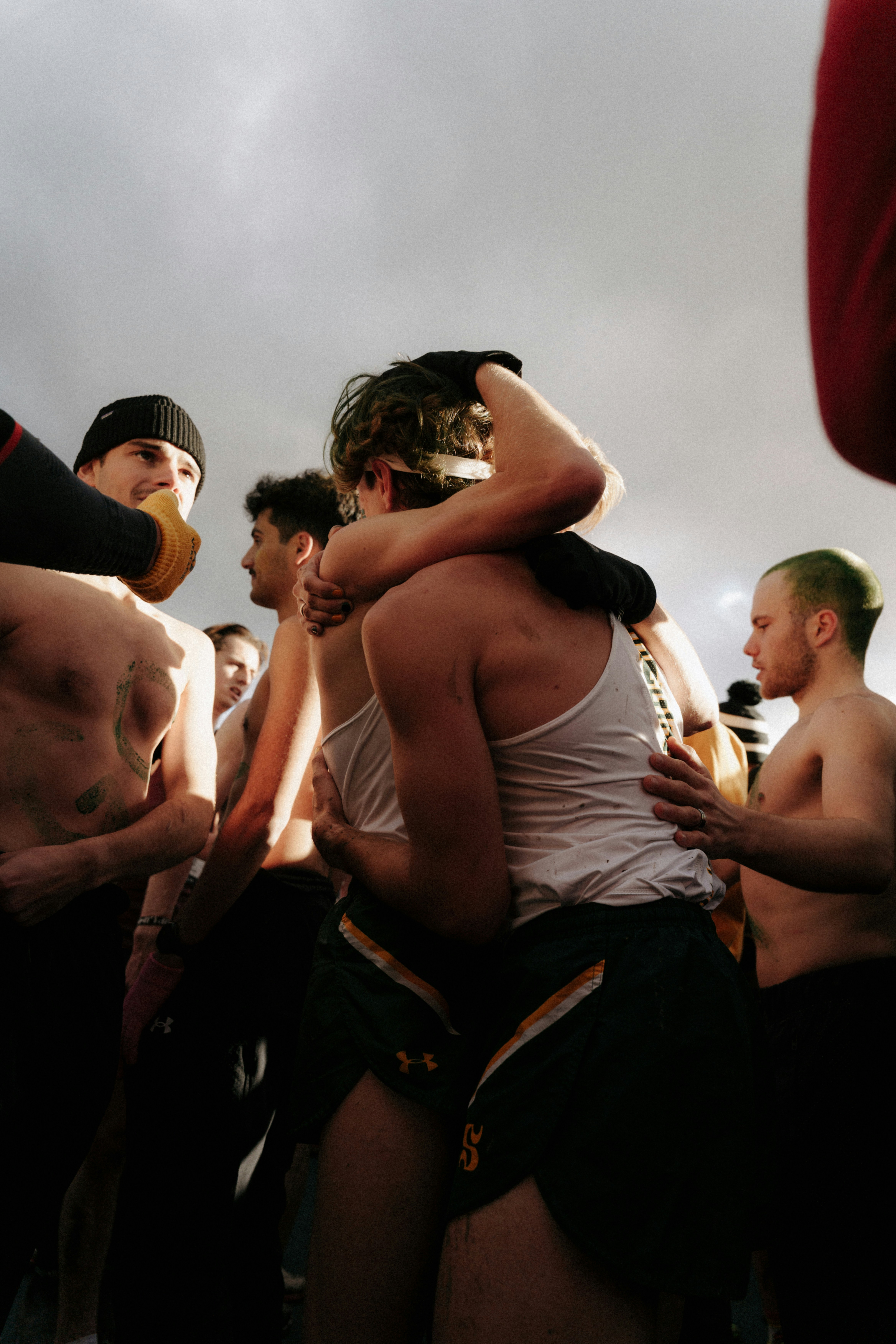 Runners embrace after a race, possibly cold, competition.