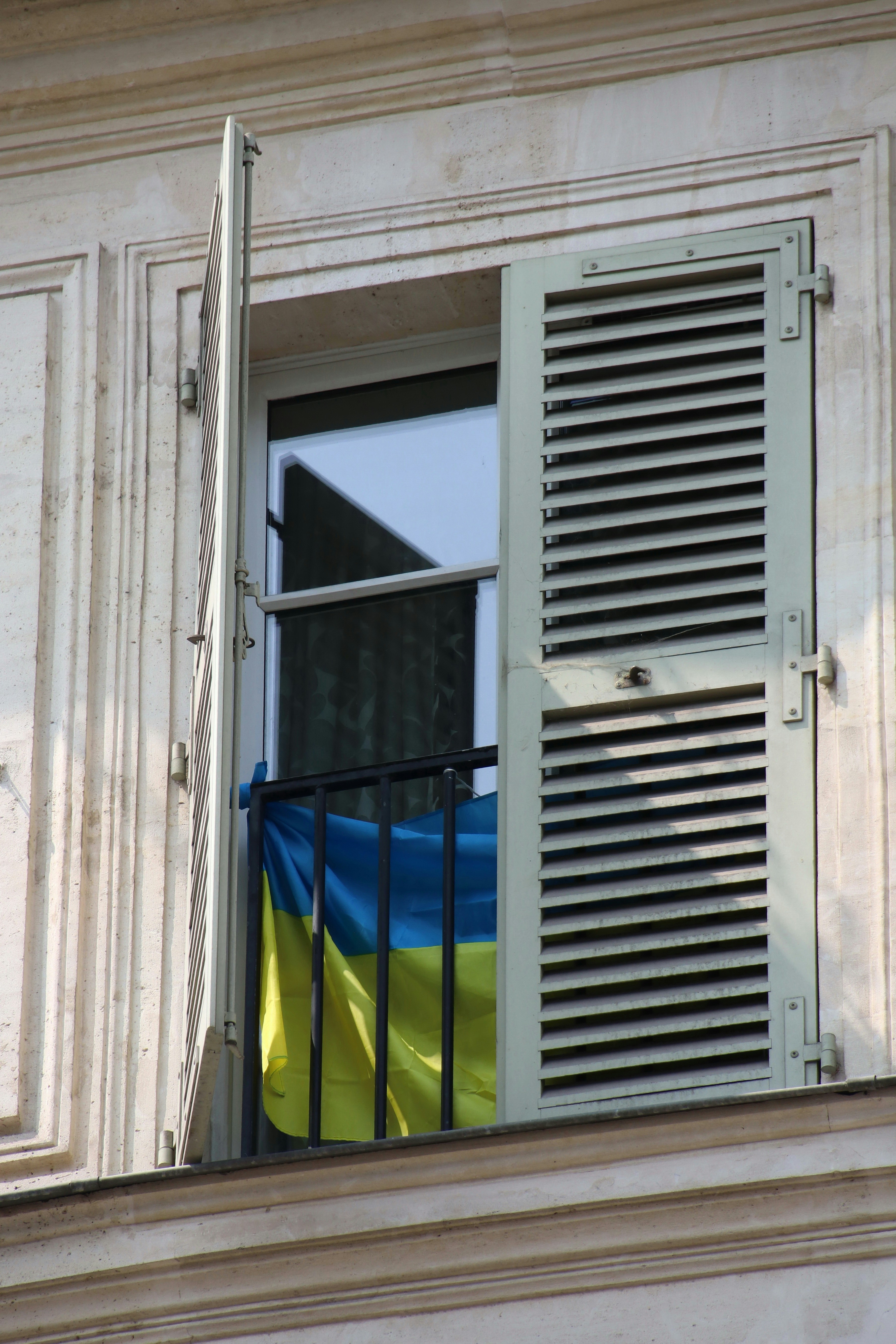 Ukrainian flag hanging from a balcony window.