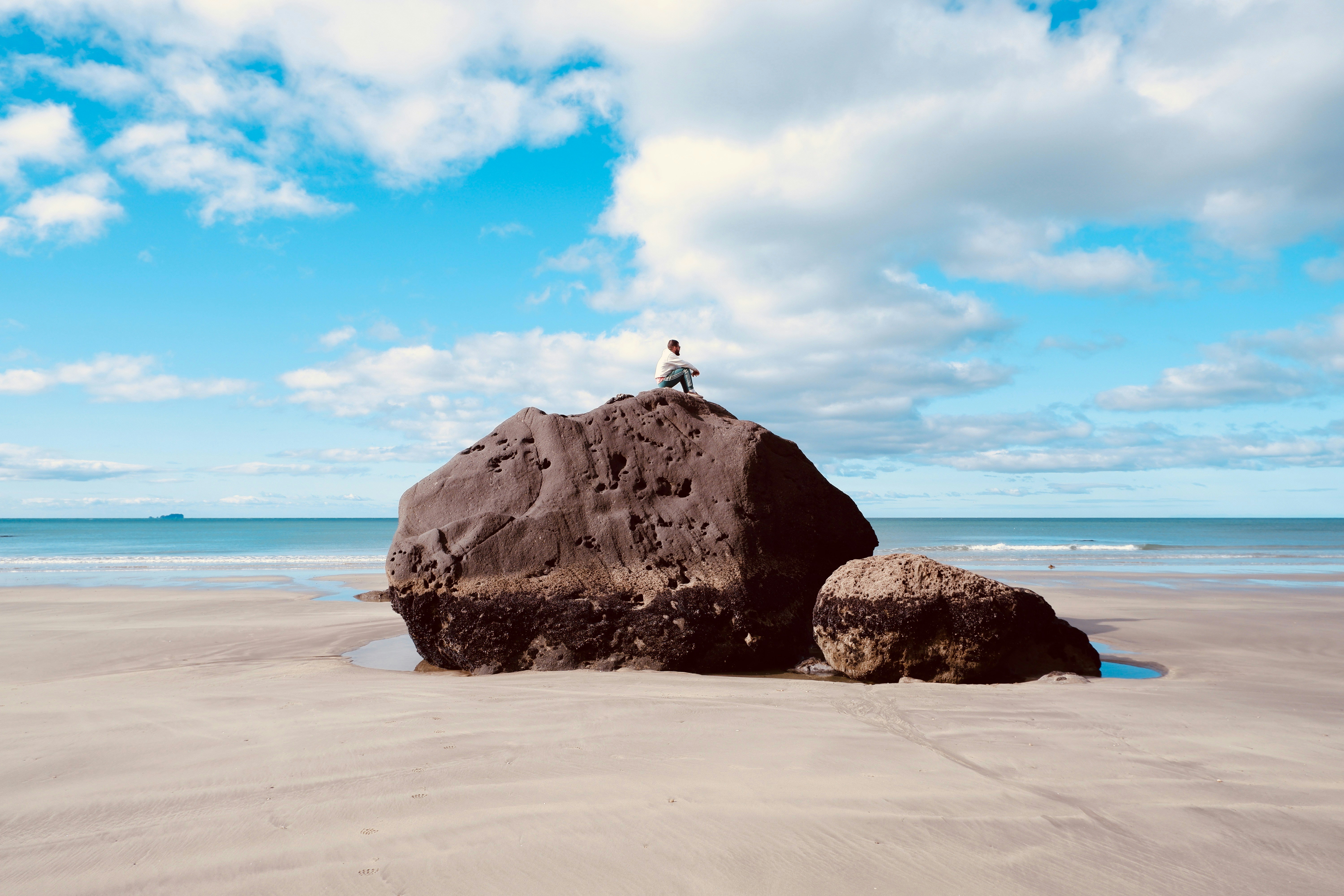 Personne assise sur un grand rocher à la plage