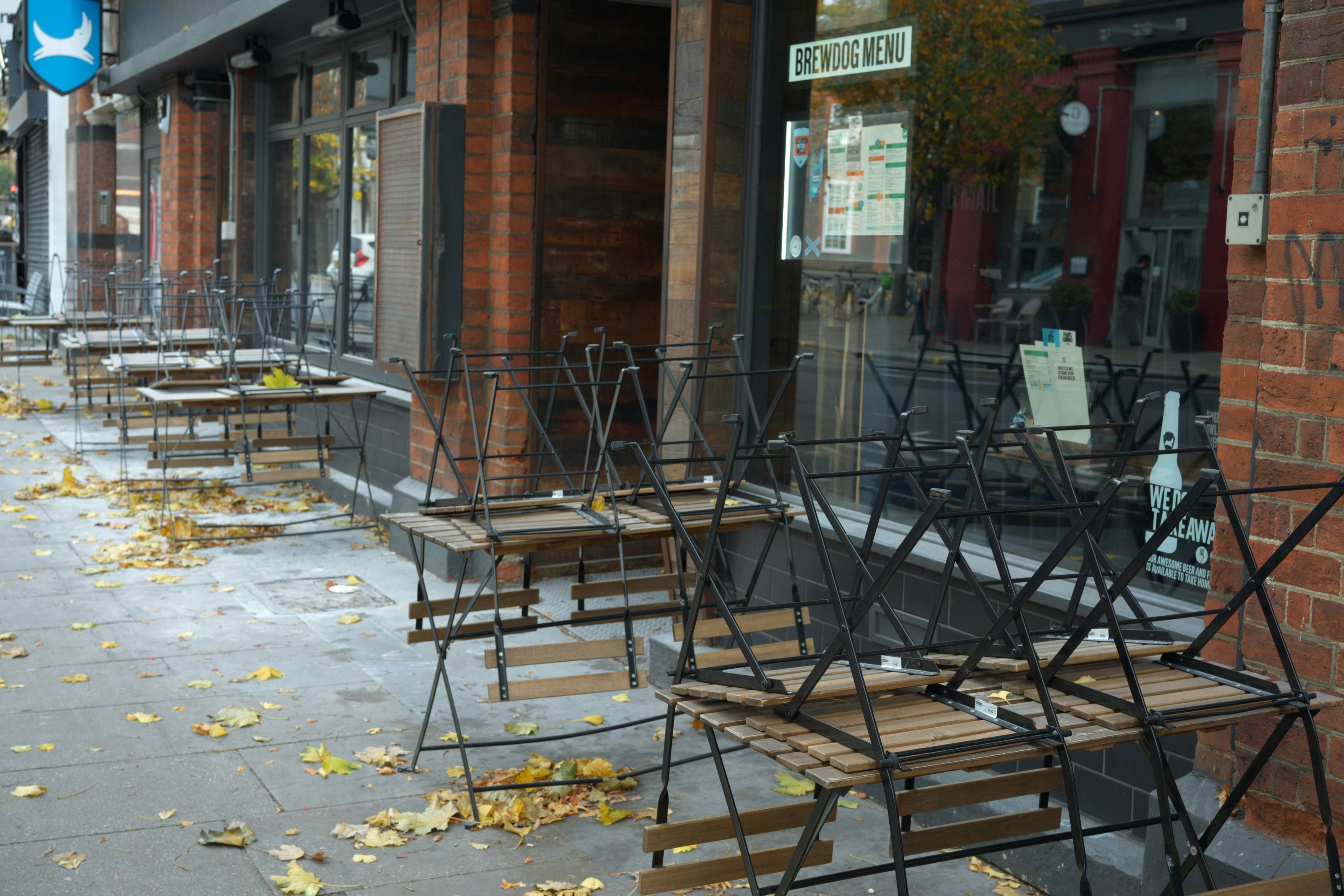 Empty outdoor cafe seating with fallen leaves