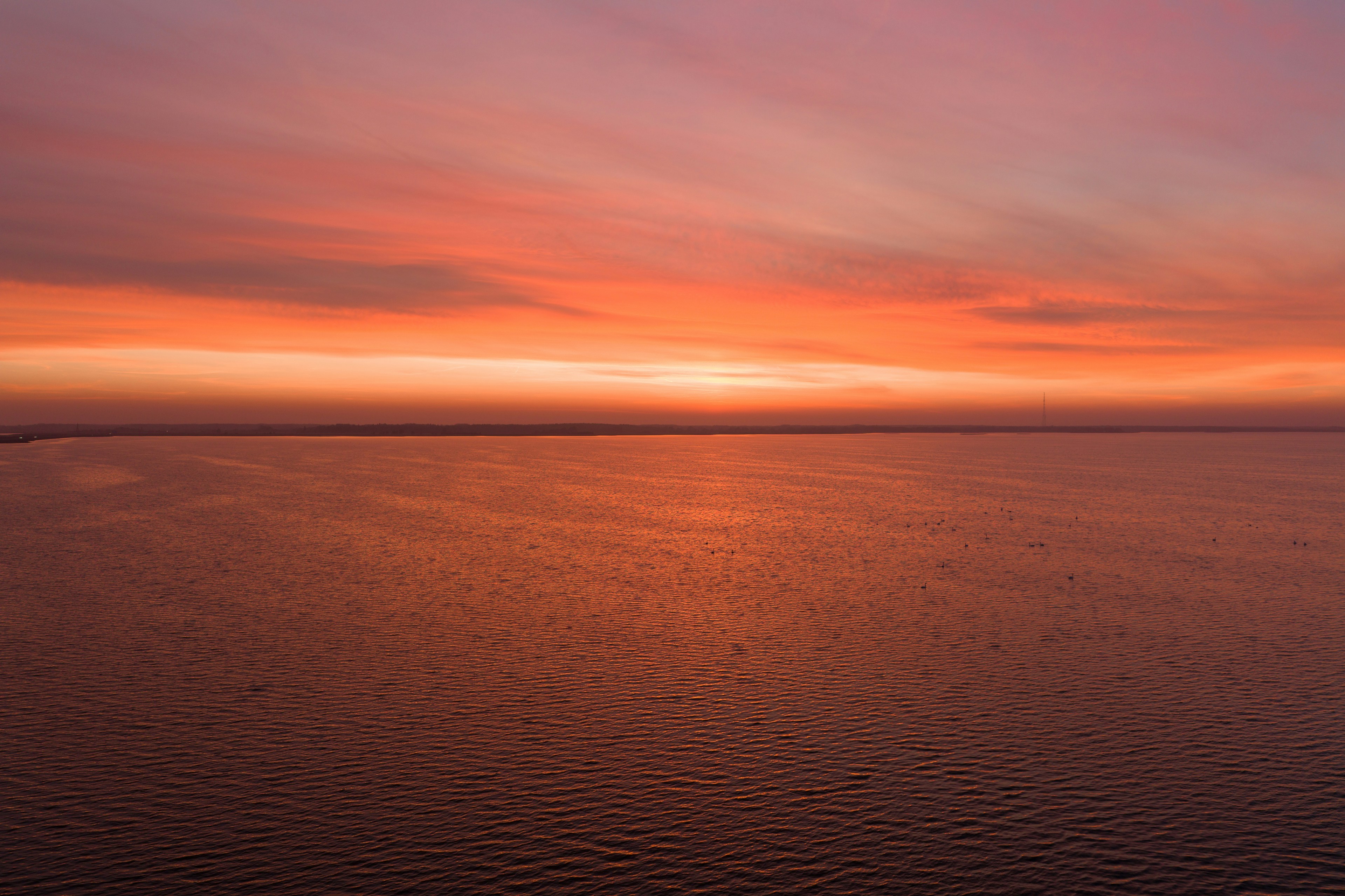 Vibrante puesta de sol sobre un océano tranquilo y reflexivo.