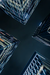 Modern skyscrapers viewed from below at night.