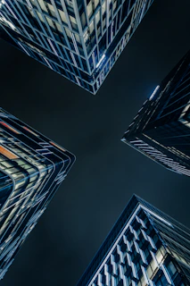 Modern skyscrapers viewed from below at night.