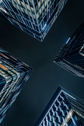 Modern skyscrapers viewed from below at night.