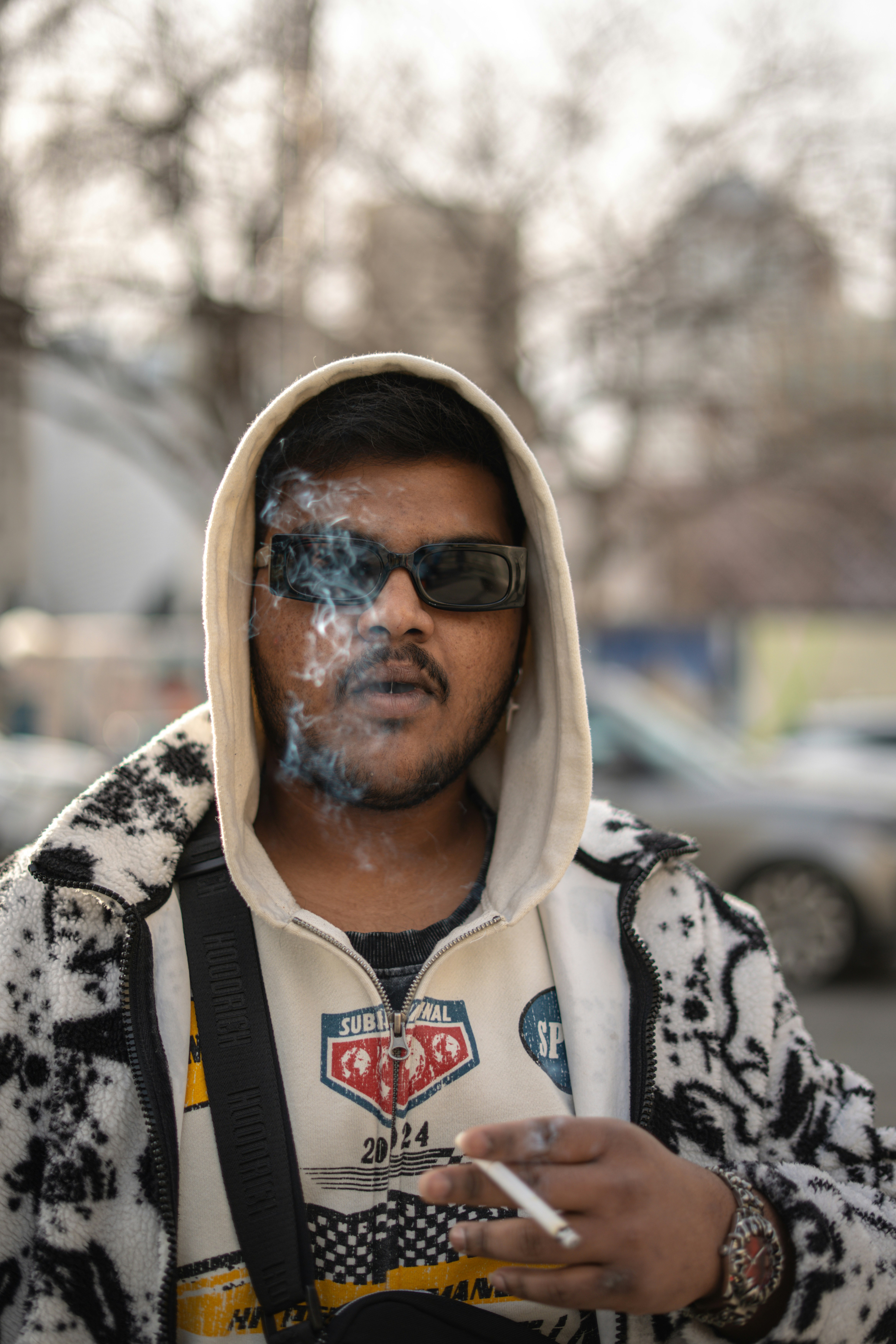 Man wearing sunglasses and hoodie smoking cigarette