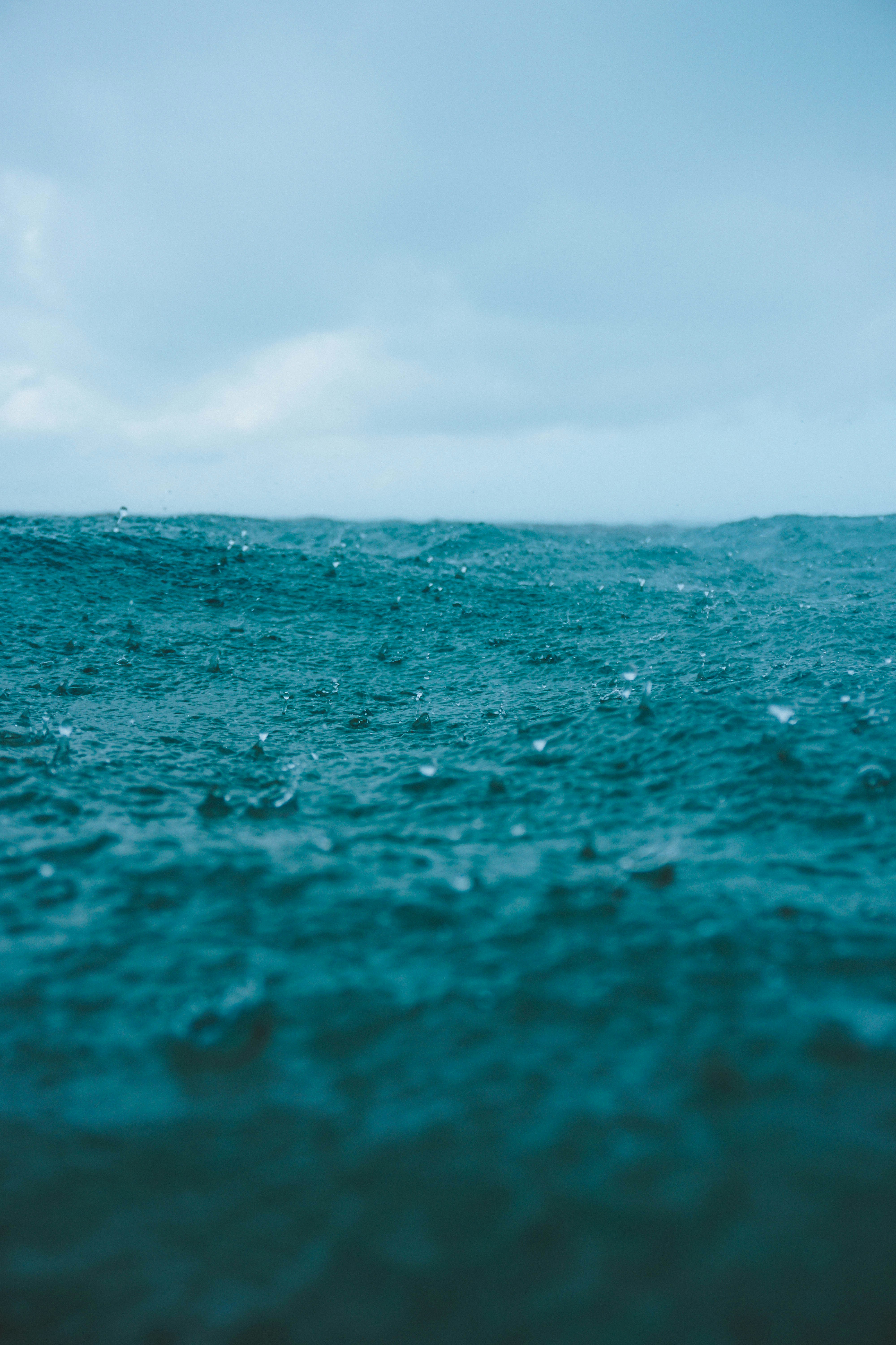 Des gouttes de pluie tombant sur la surface bleue agitée de l’océan.