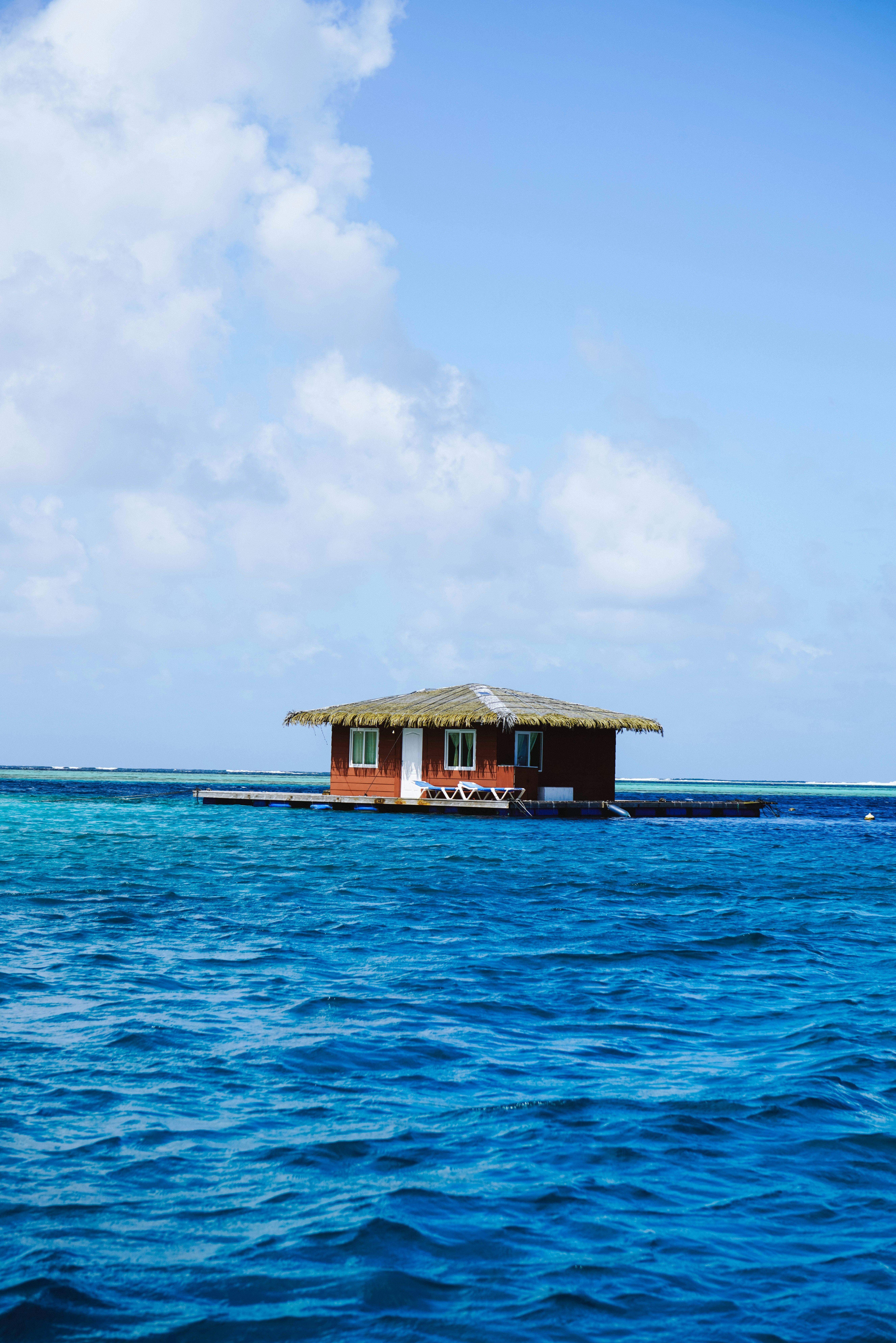 Petite maison en bois flottant sur le bleu de l’océan.