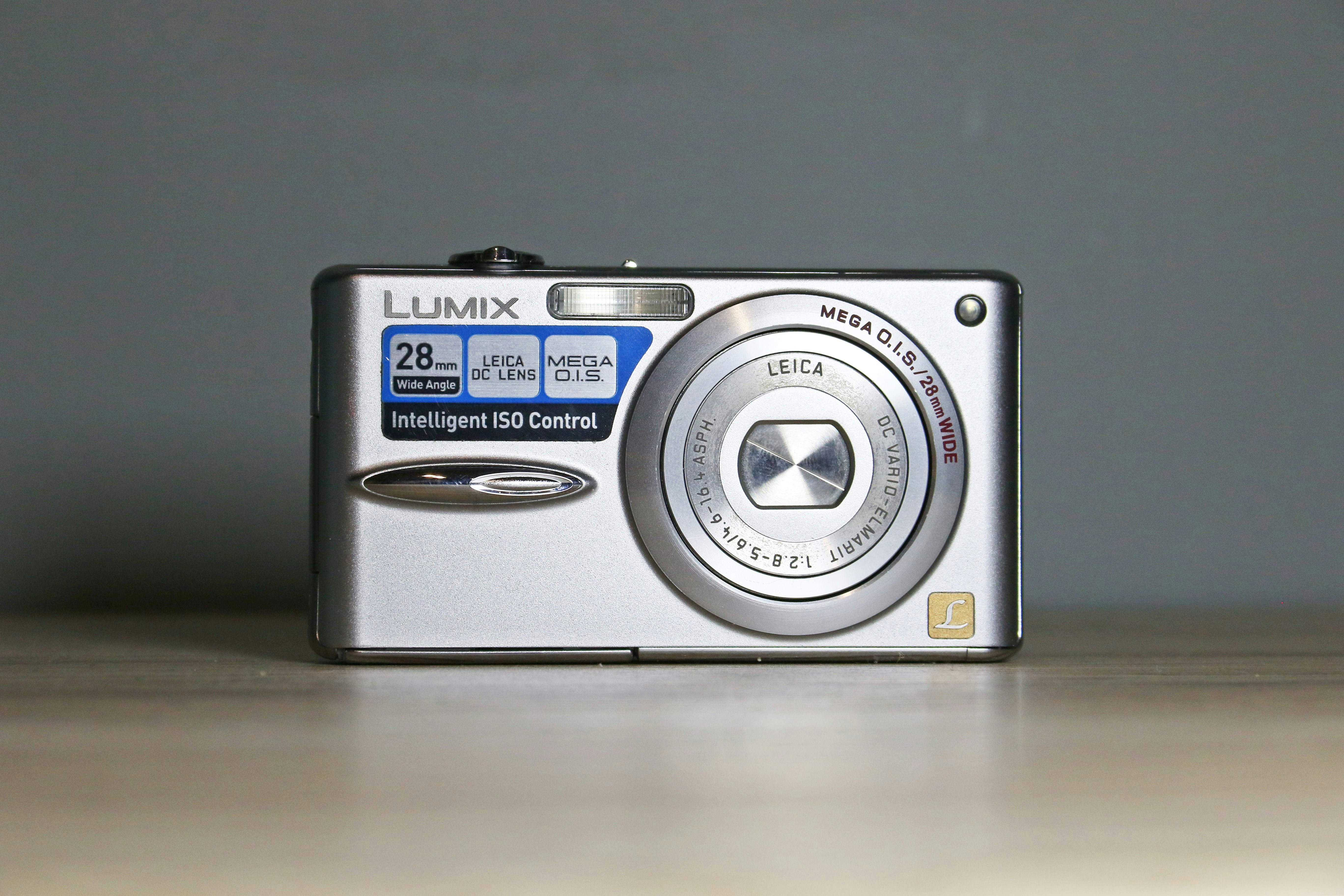 A silver lumix digital camera on a wooden surface.