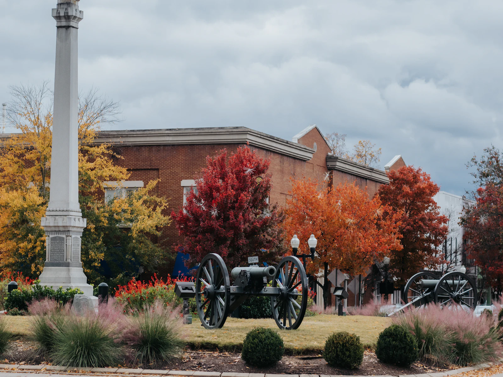 A monument and cannons on a town square in autumn.