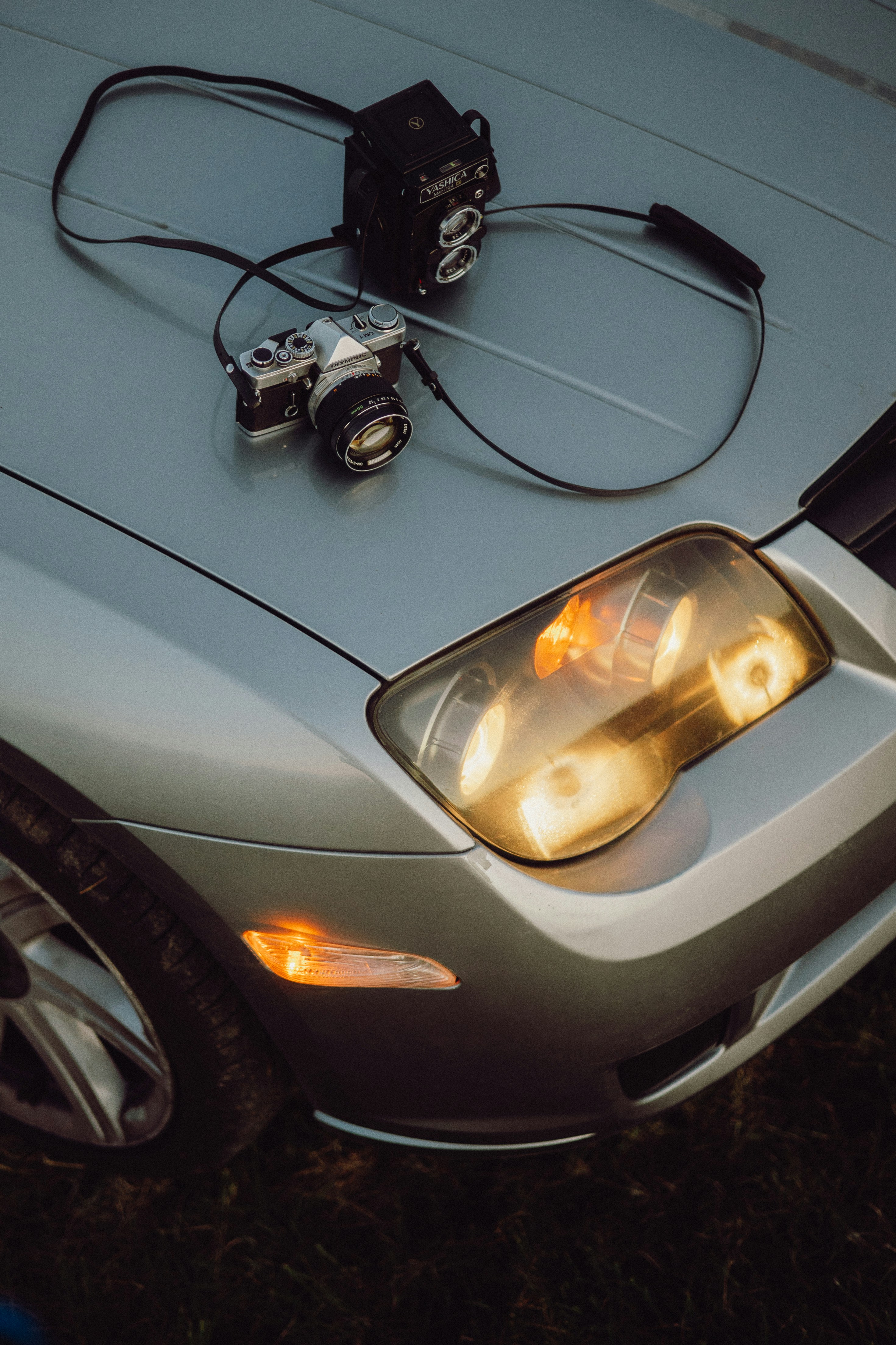 Two vintage cameras on a silver car hood