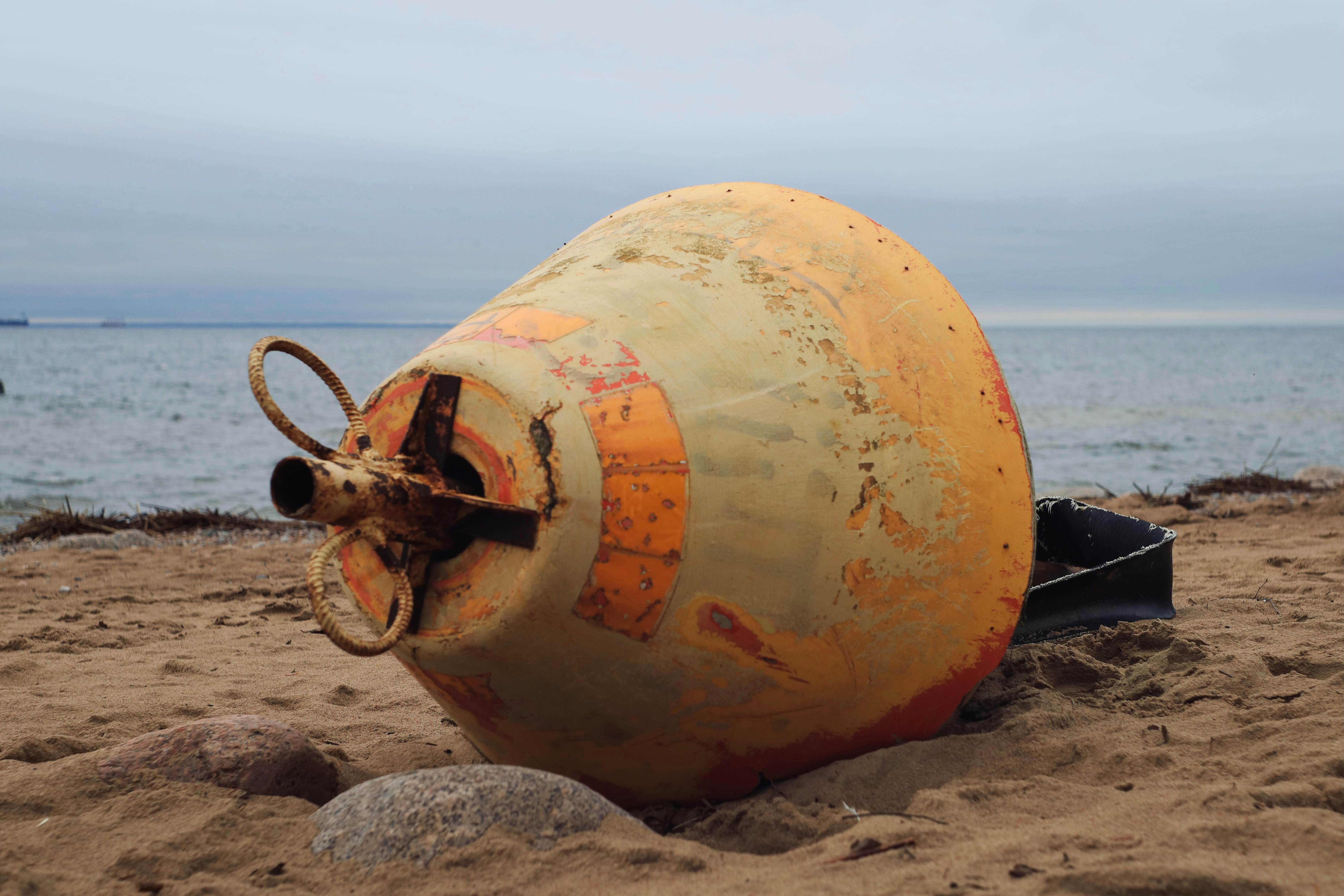 Eine große orangefarbene Boje ruht auf einem Sandstrand.