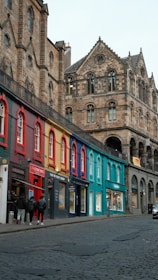 Colorful shops line a cobblestone street with historic buildings.