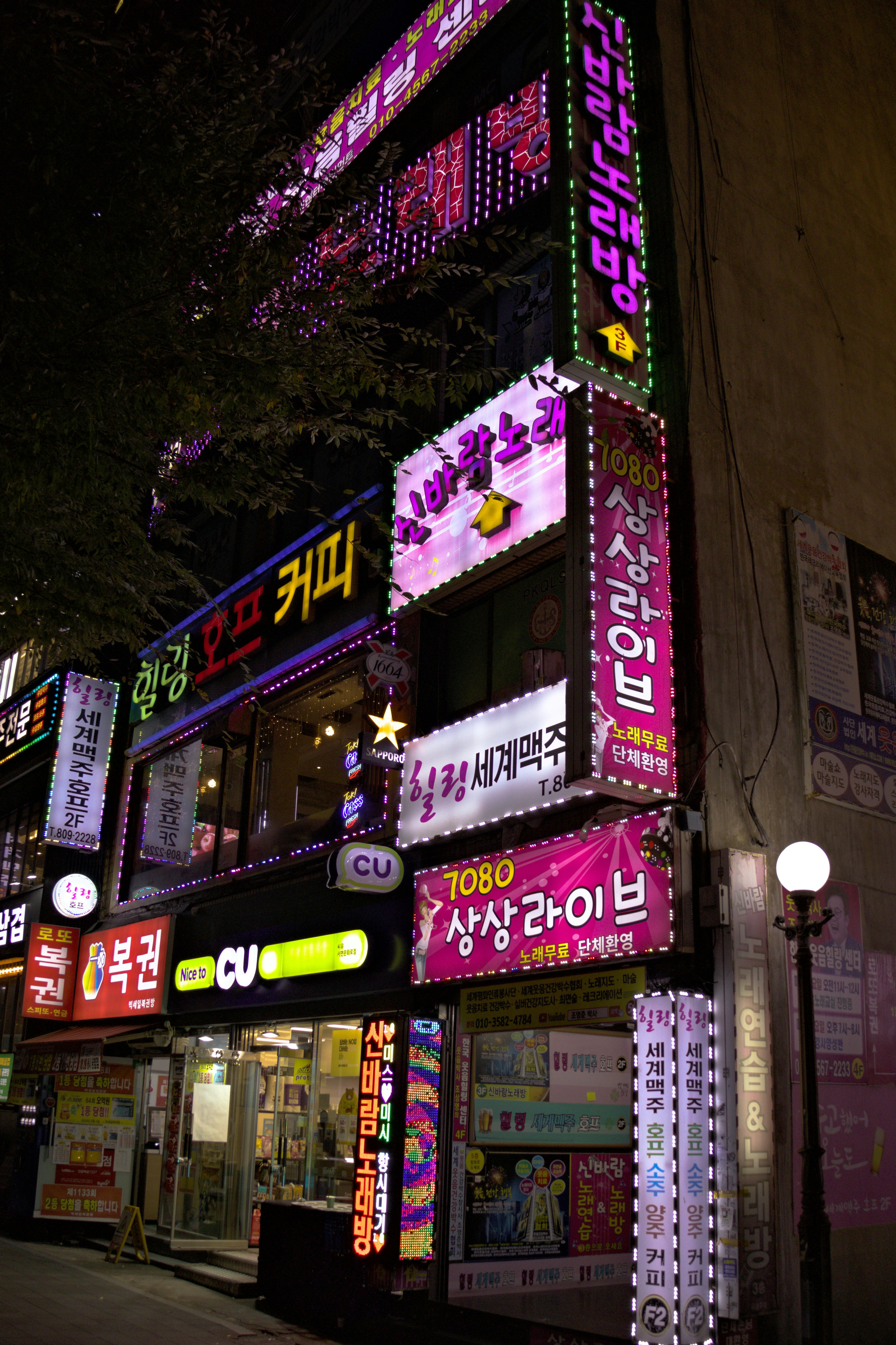 Brightly lit storefronts at night with korean text.
