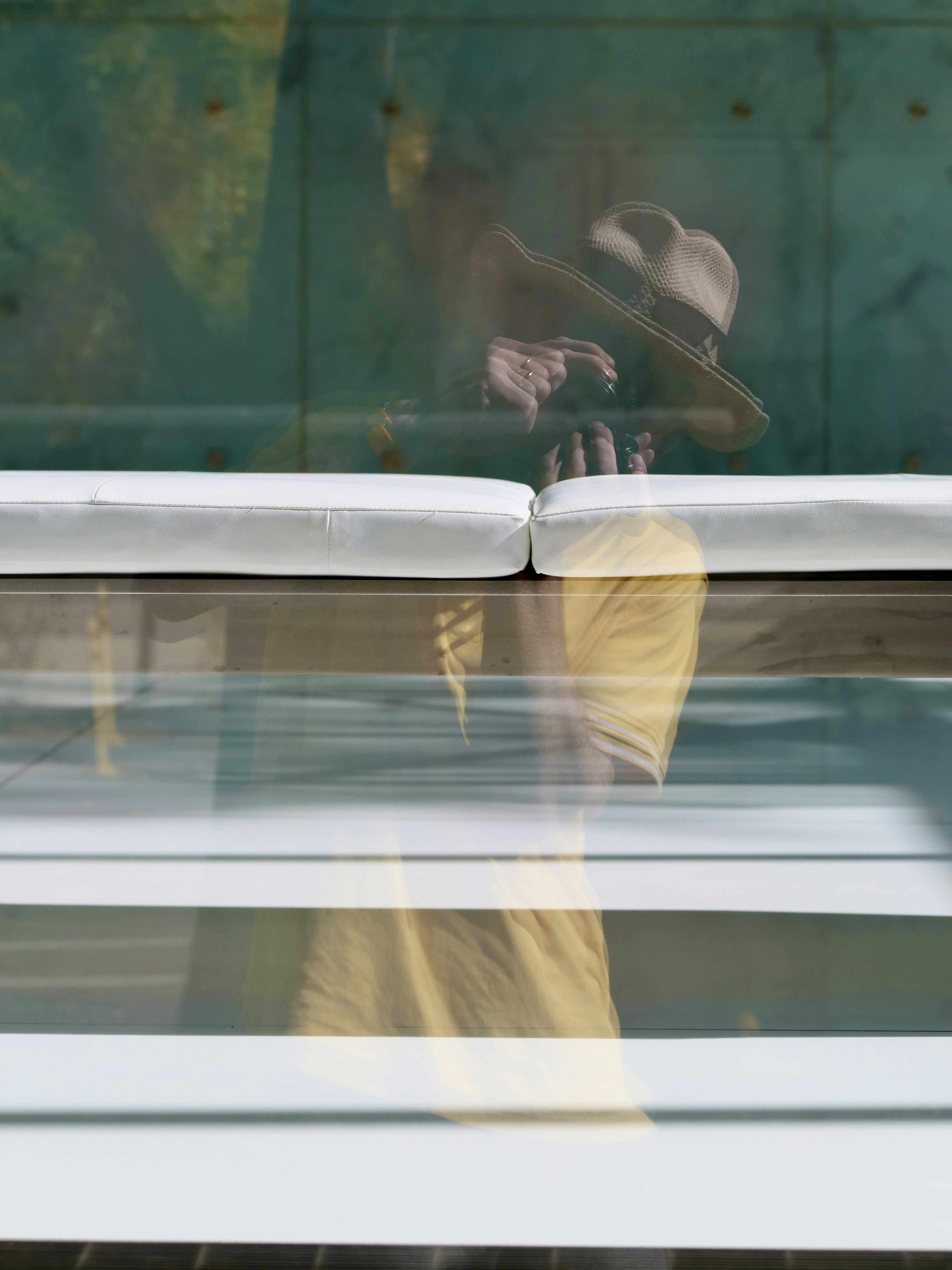 Person wearing a hat reflected in glass