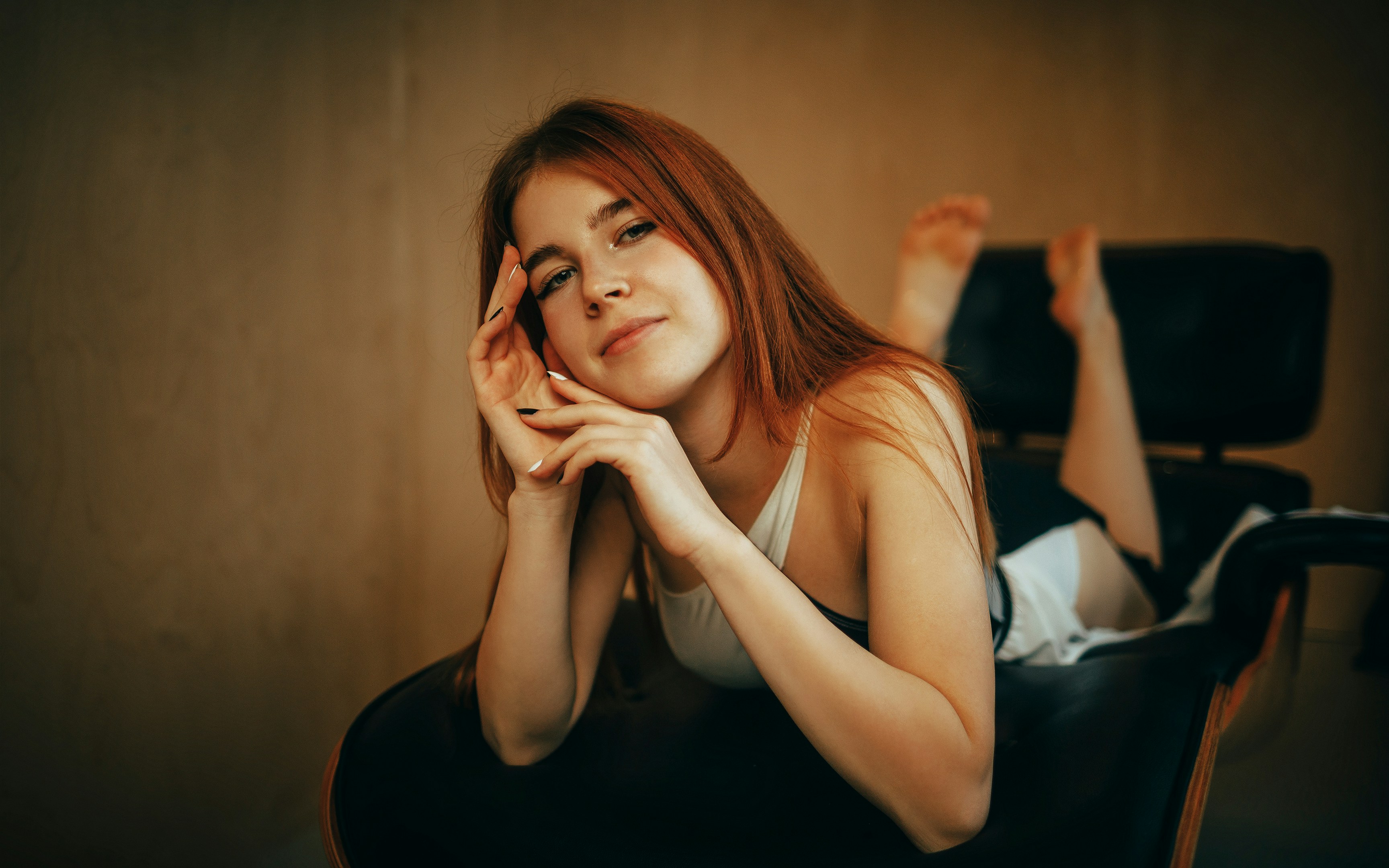 Young woman with red hair lying on a chair
