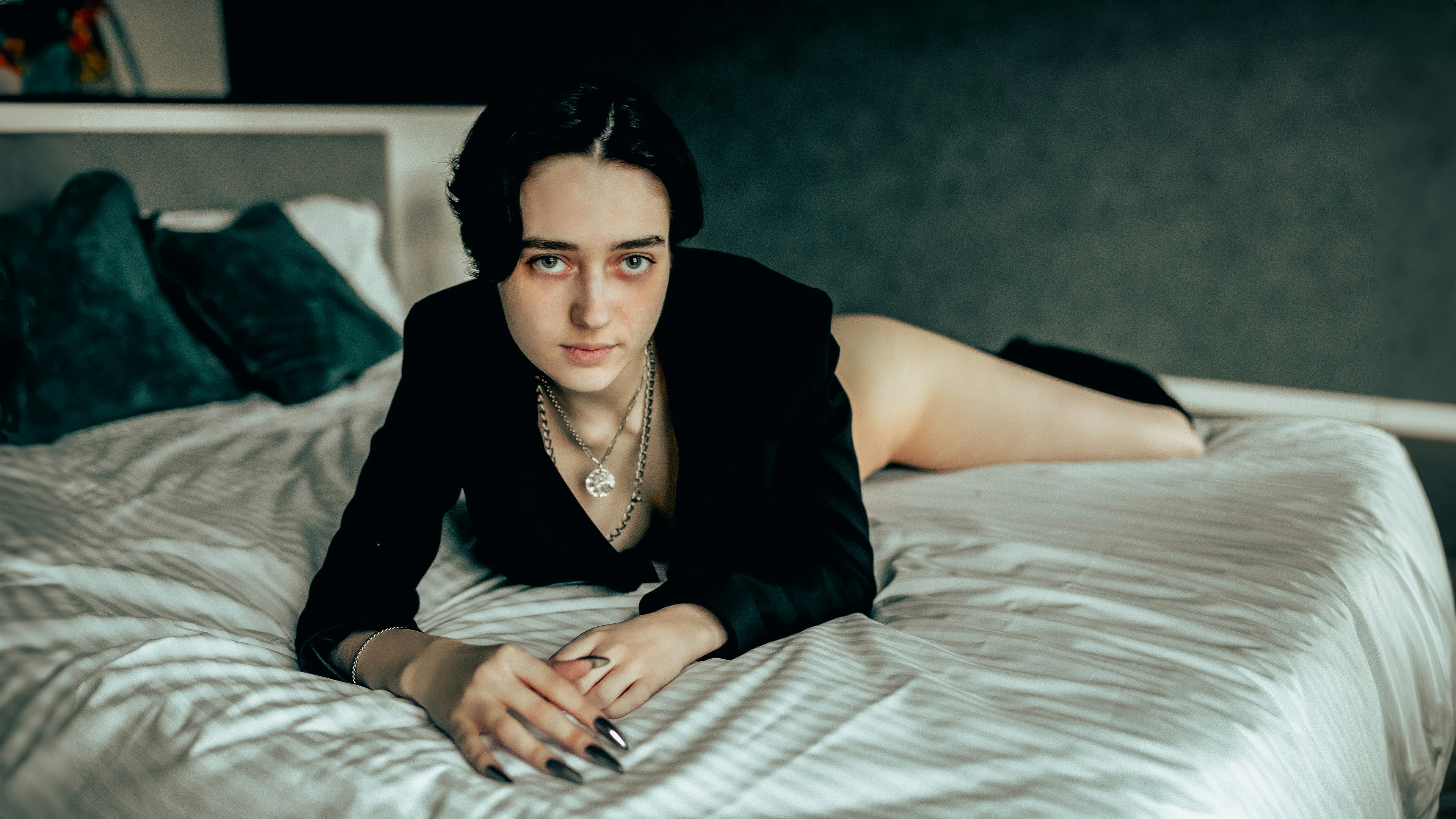 Woman in black blazer lying on a bed