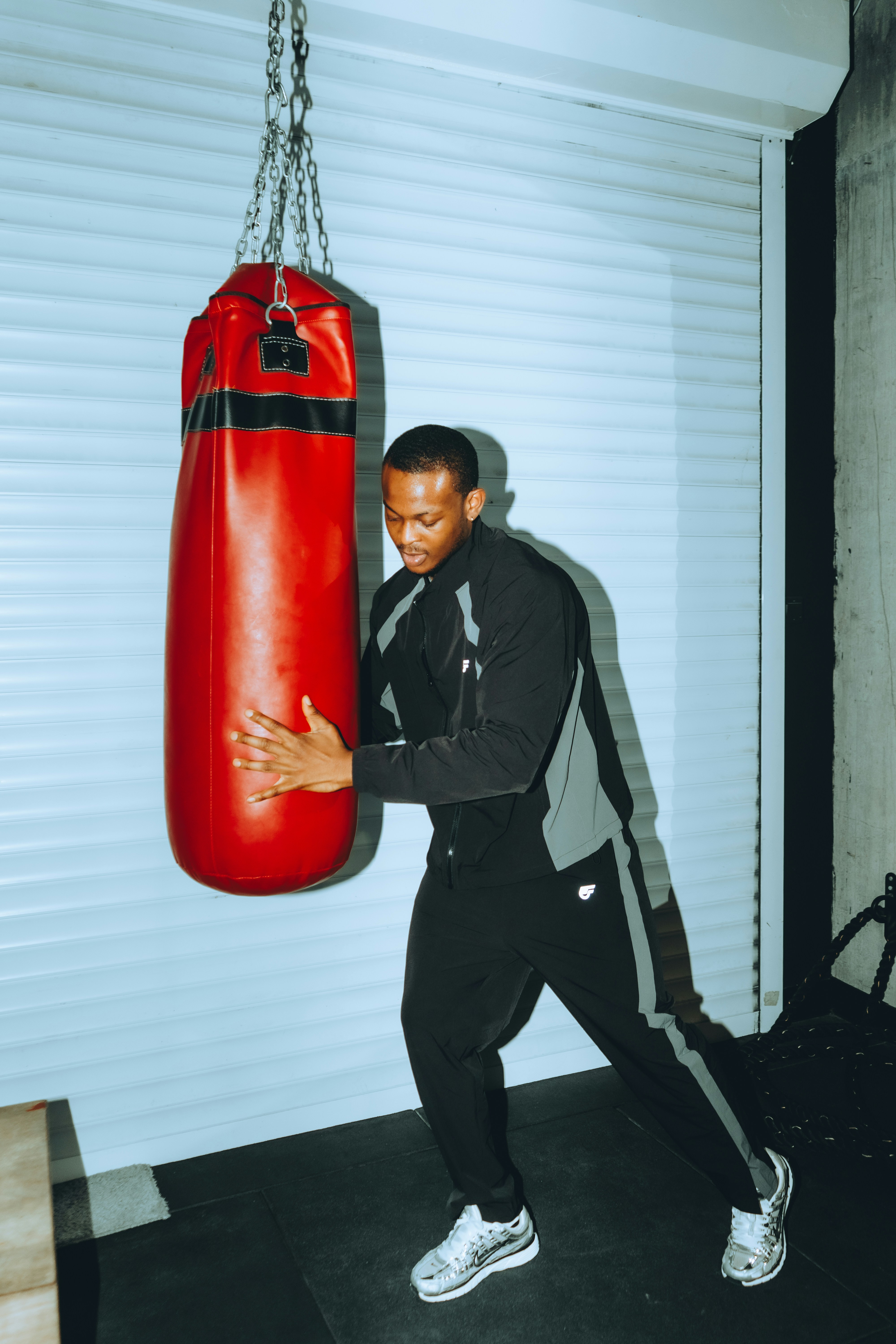 Man in athletic wear punching a red heavy bag.