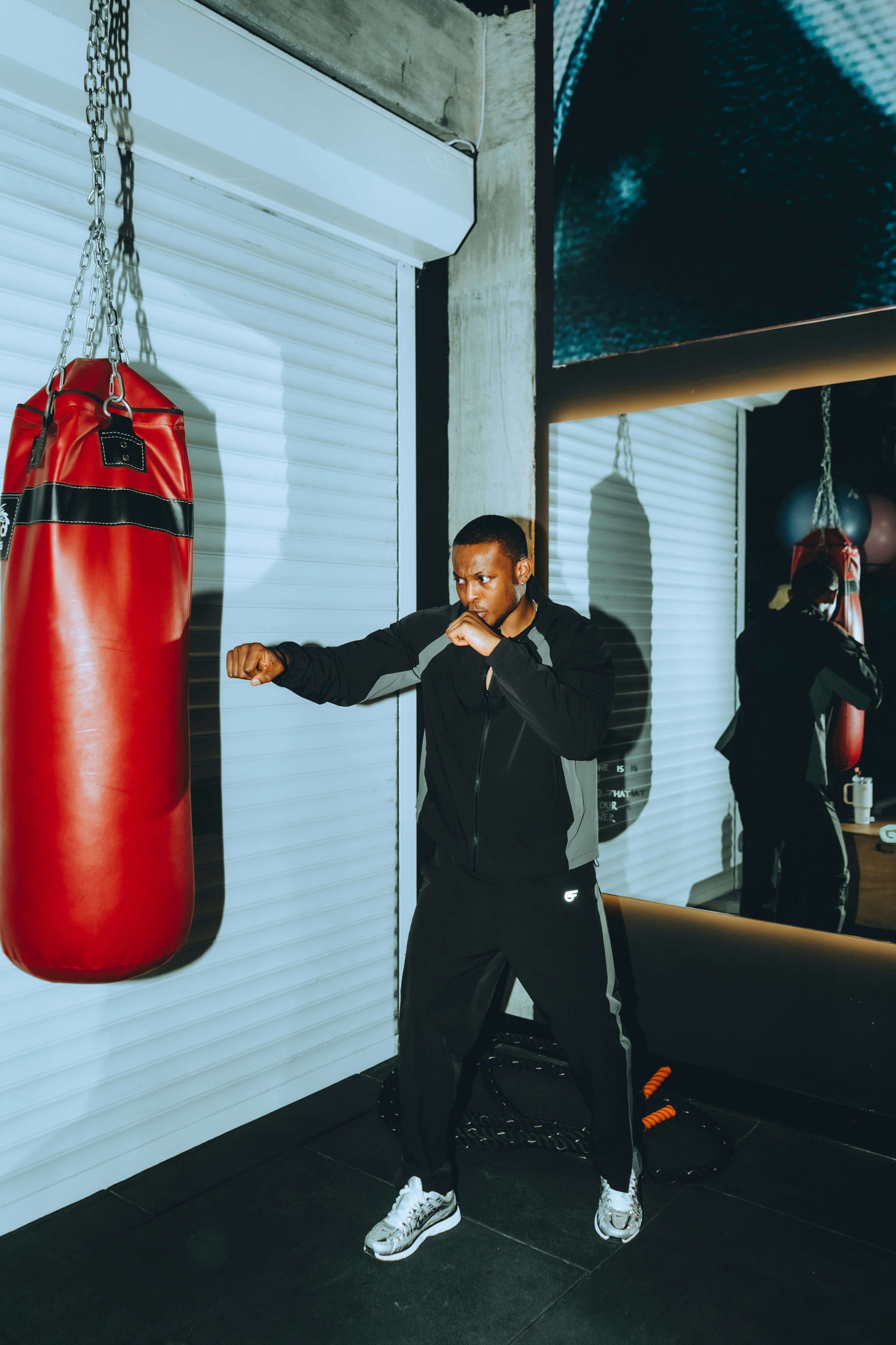 Man throwing a jab at a red heavy bag in a boxing gym