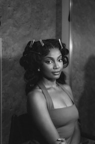 A woman with curlers in her hair looks forward.