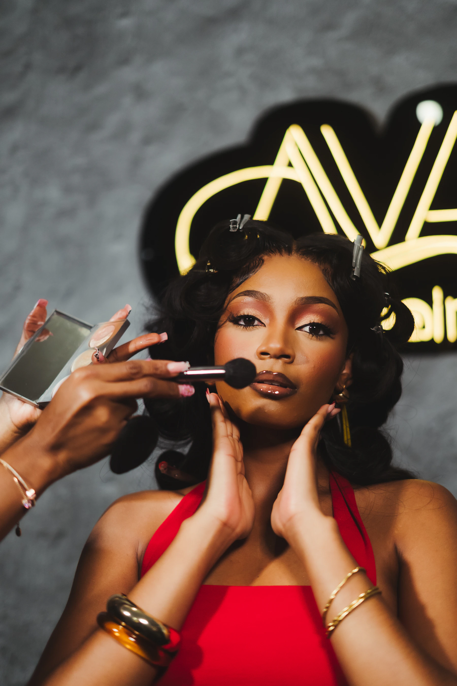 Woman applying makeup with a beauty brush while looking into a mirror