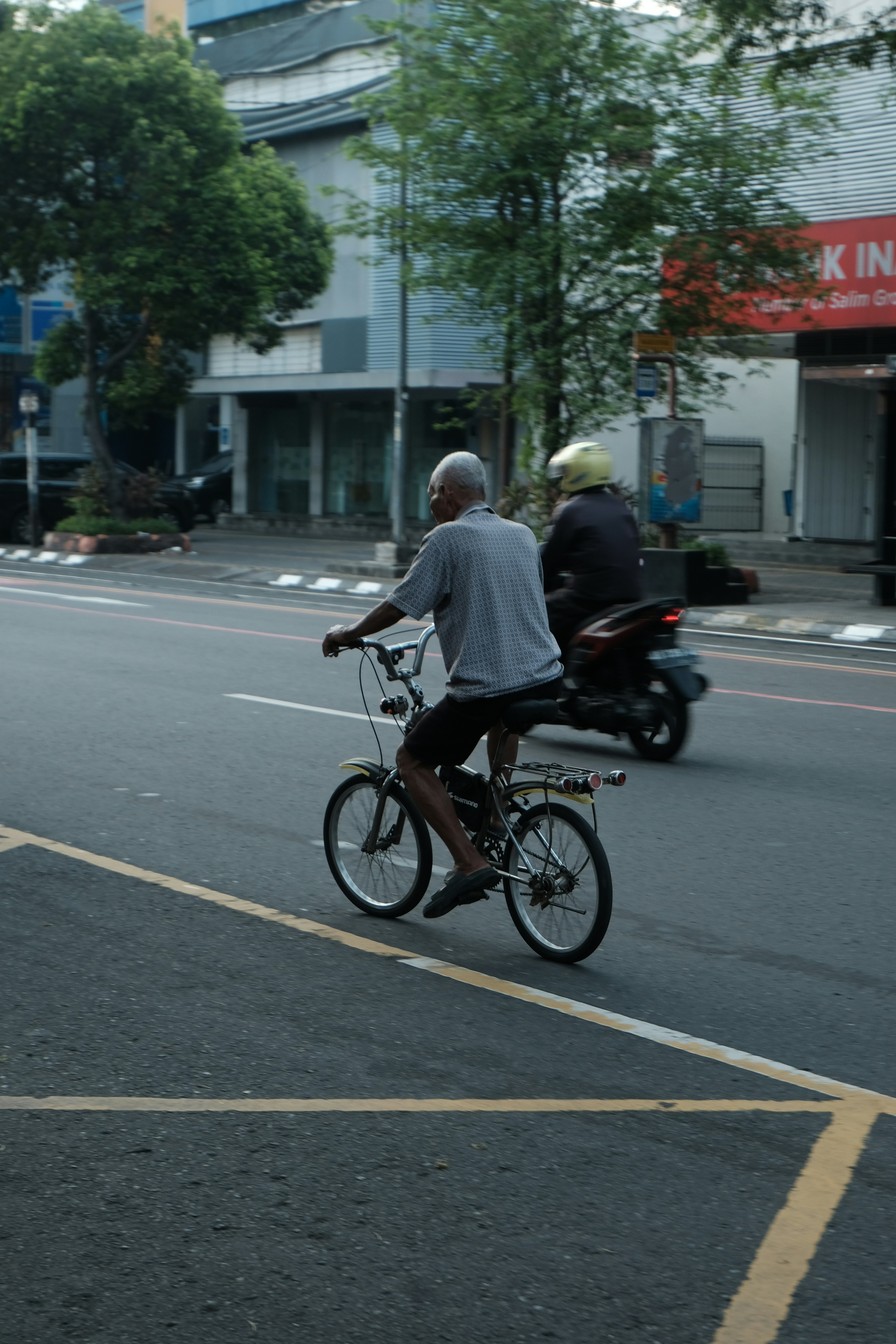 Elderly man rides bicycle on city street.