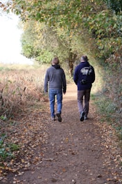 Two men walking down a leaf-covered path