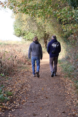 Two men walking down a leaf-covered path