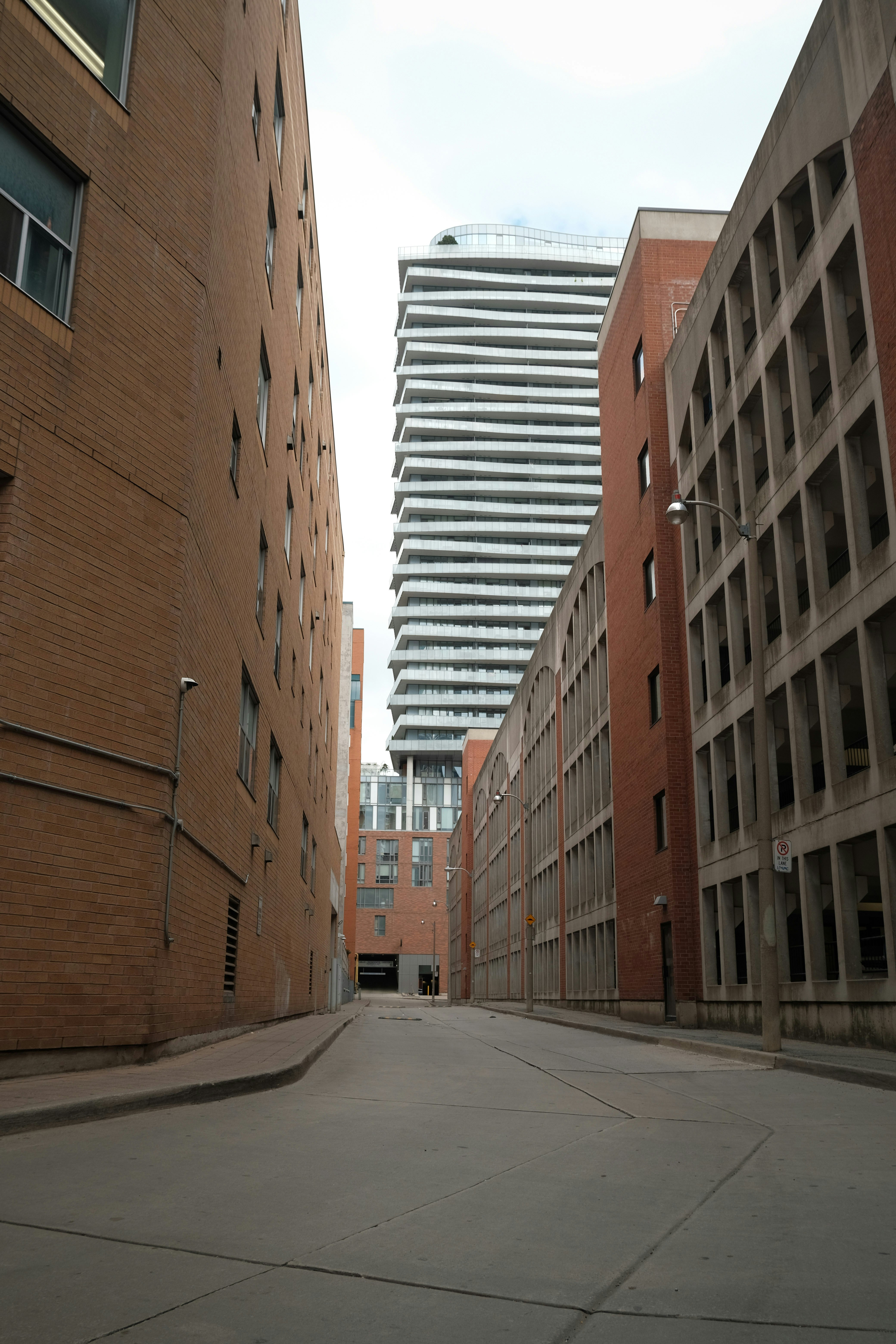Brick buildings line a narrow street leading to modern skyscraper.