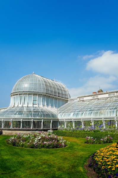 Glass conservatory with manicured gardens under blue sky