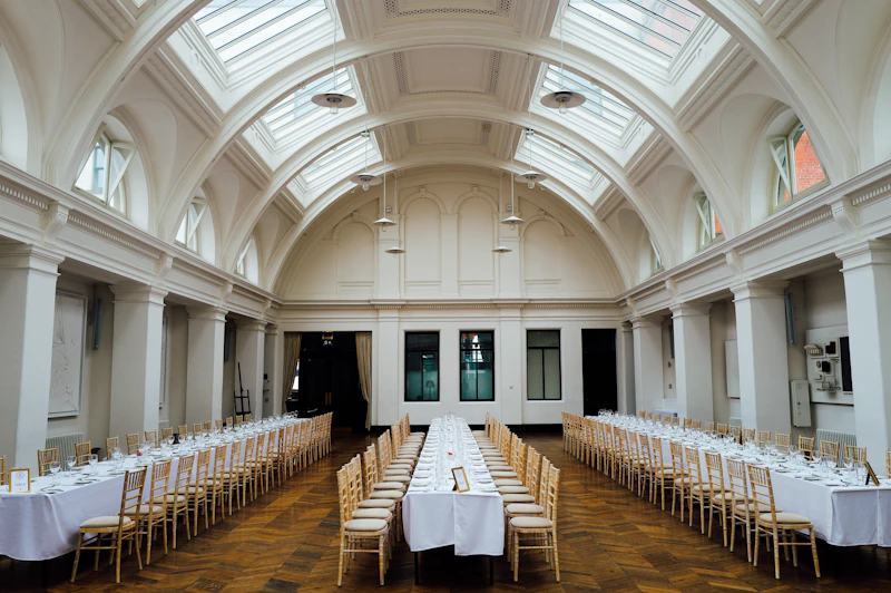 Long banquet tables set beneath the arched skylights of a grand hall