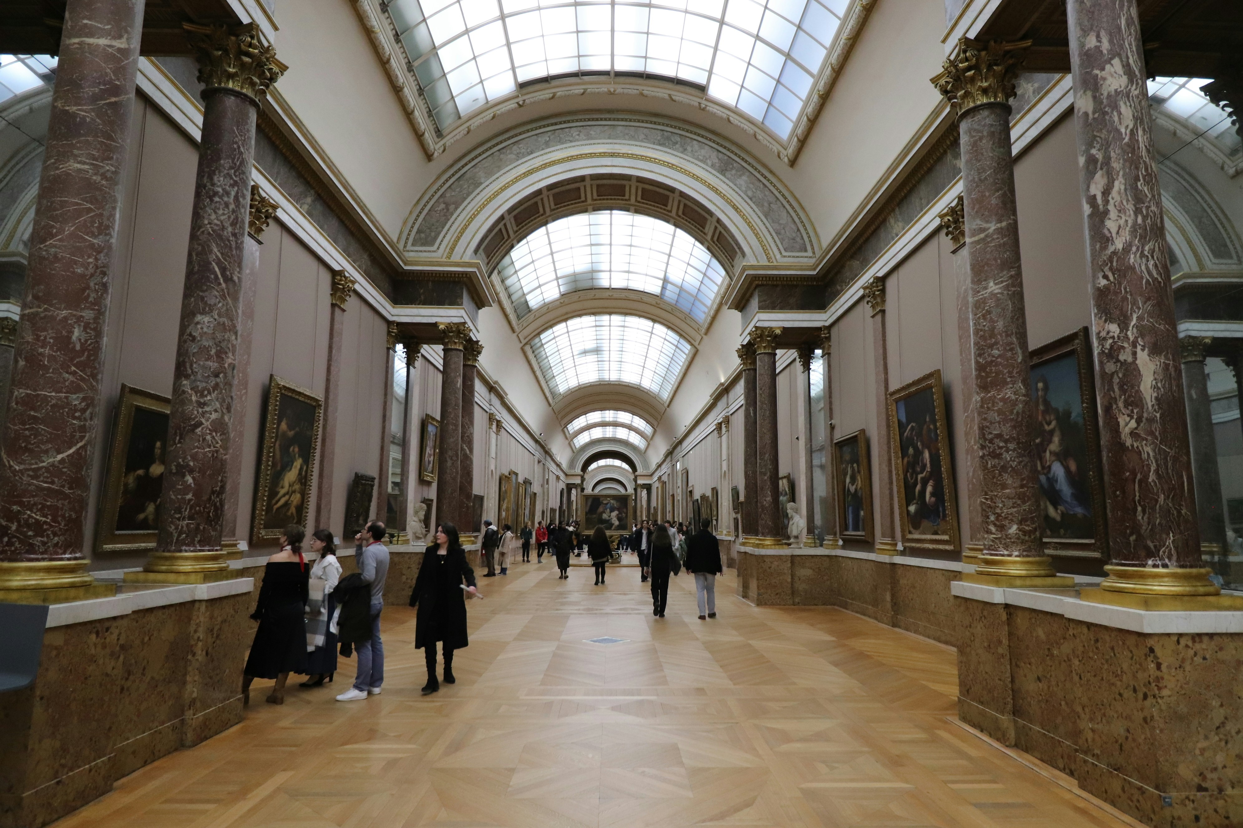 People walking through a grand art museum gallery