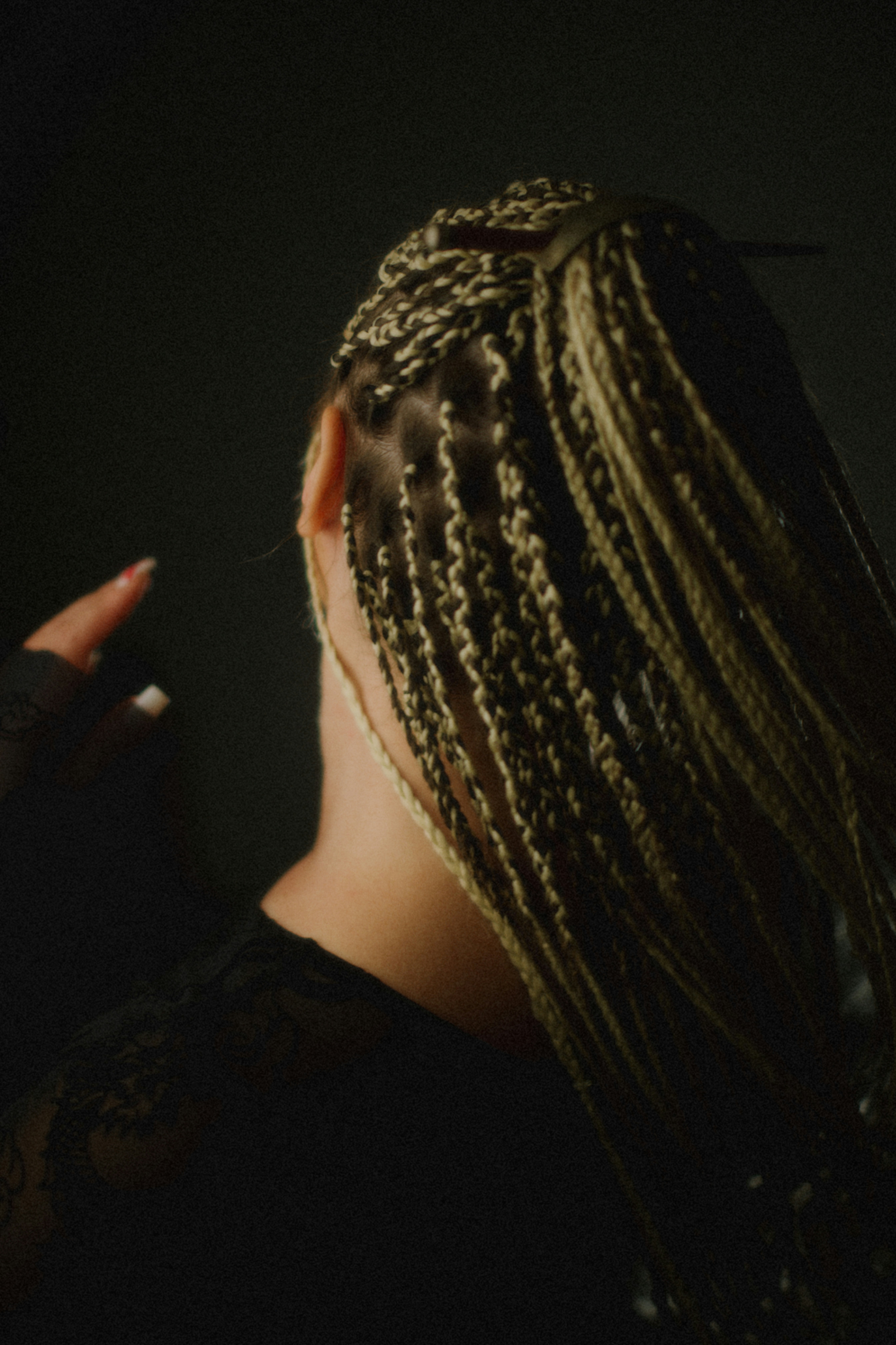 Woman with blonde box braids in dark setting
