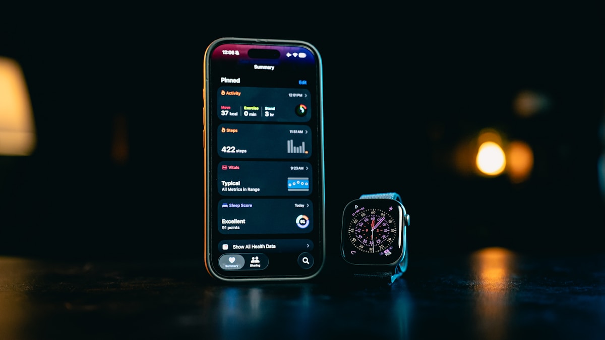 Smartphone and smartwatch side by side displaying fitness app screens at night