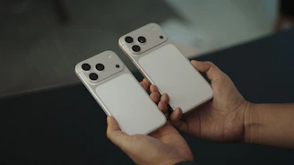 Two white smartphones held by hands
