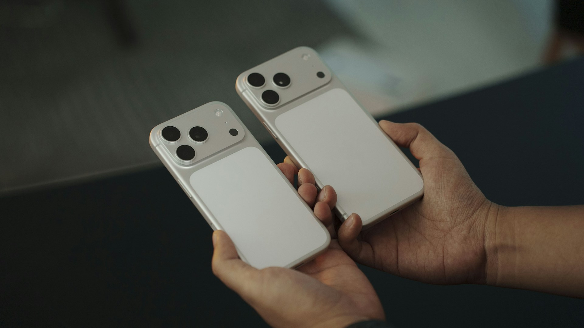 Two white smartphones held by hands