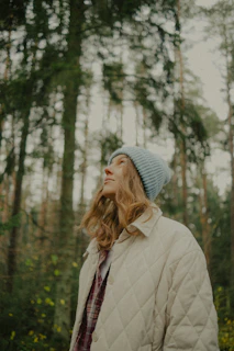 Woman wearing a light blue beanie in a forest.