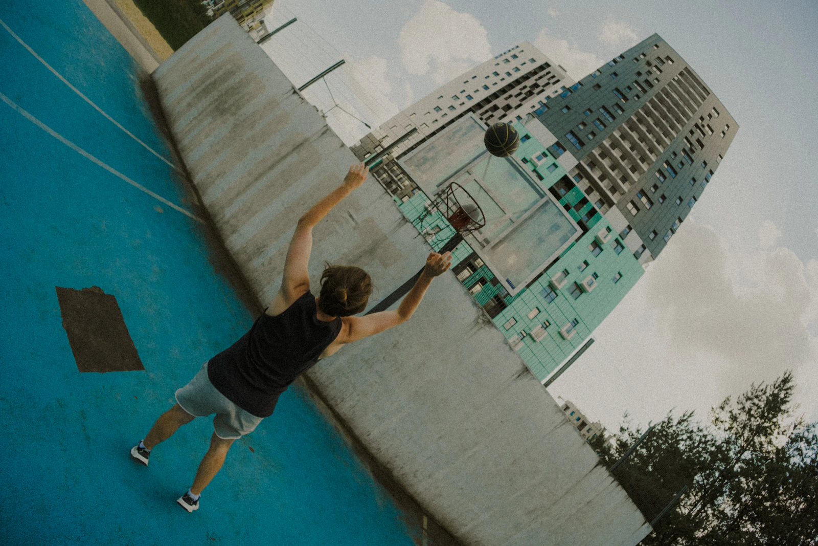 Male athlete taking a basketball shot on an outdoor court in modern sportswear