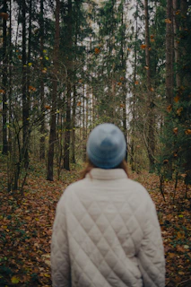 Person in a blue hat walks through autumn forest