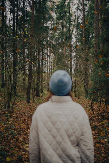 Person in a blue hat walks through autumn forest