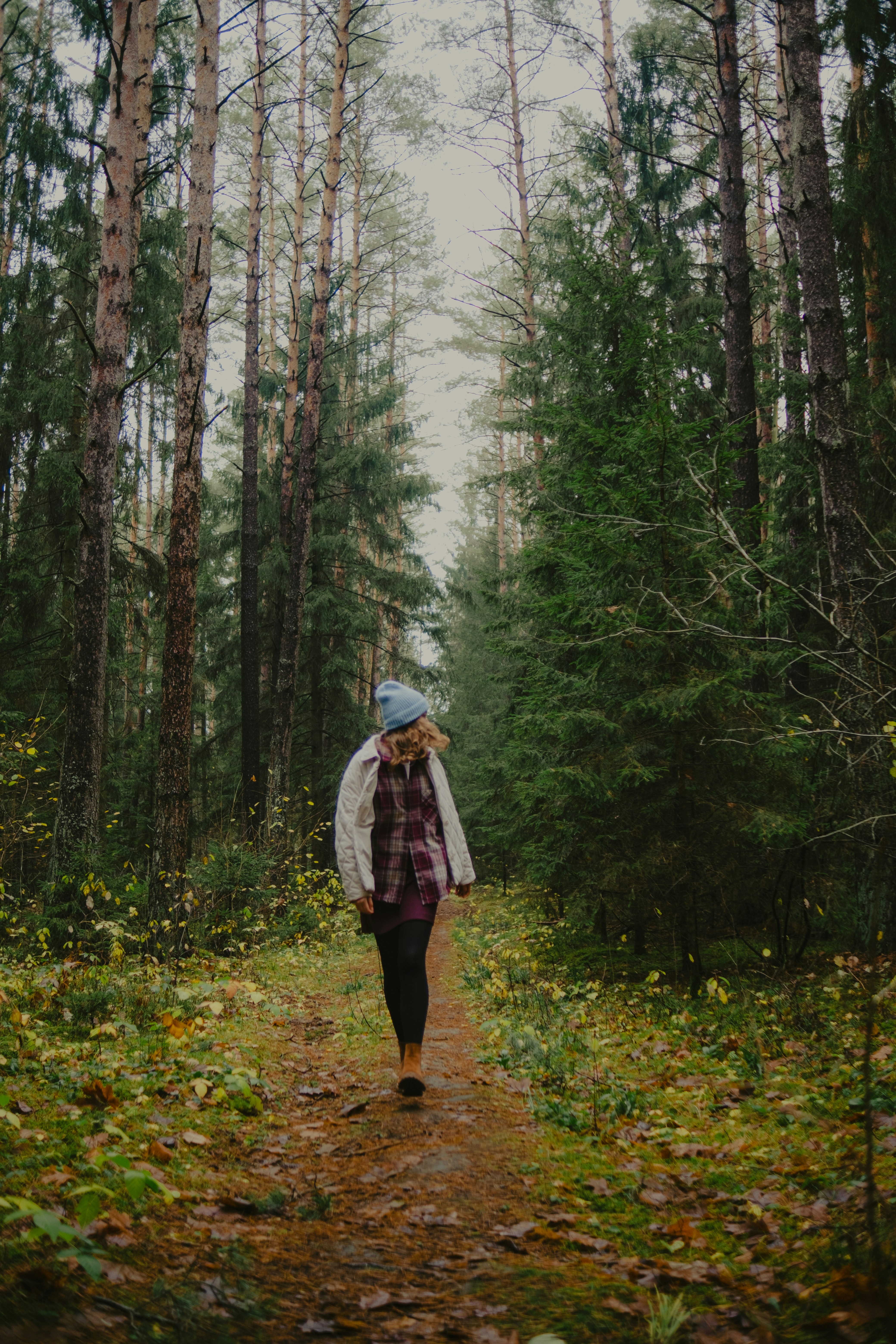 Woman walking on path through autumn forest