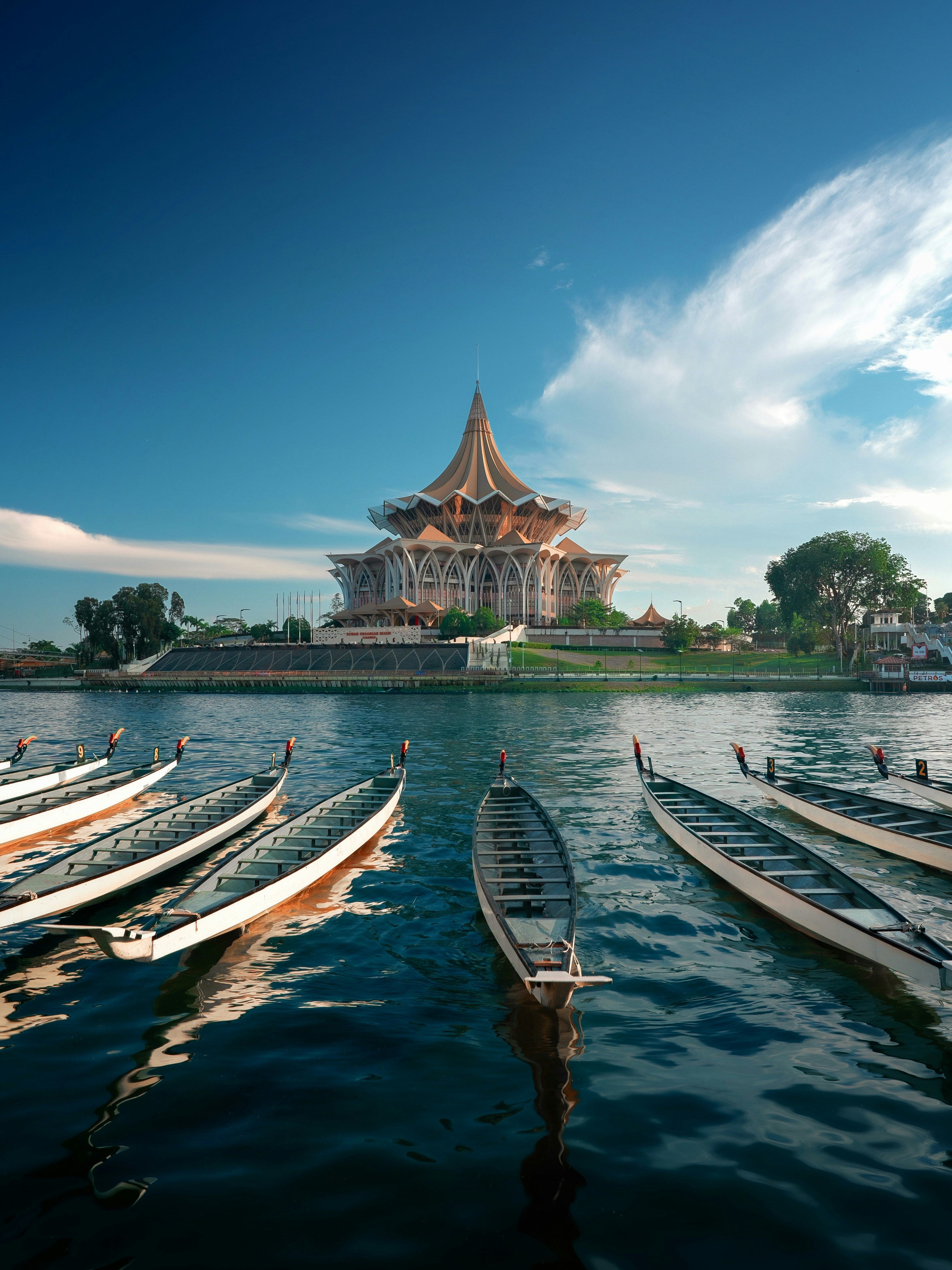 Dragon boats docked on a river with a building.