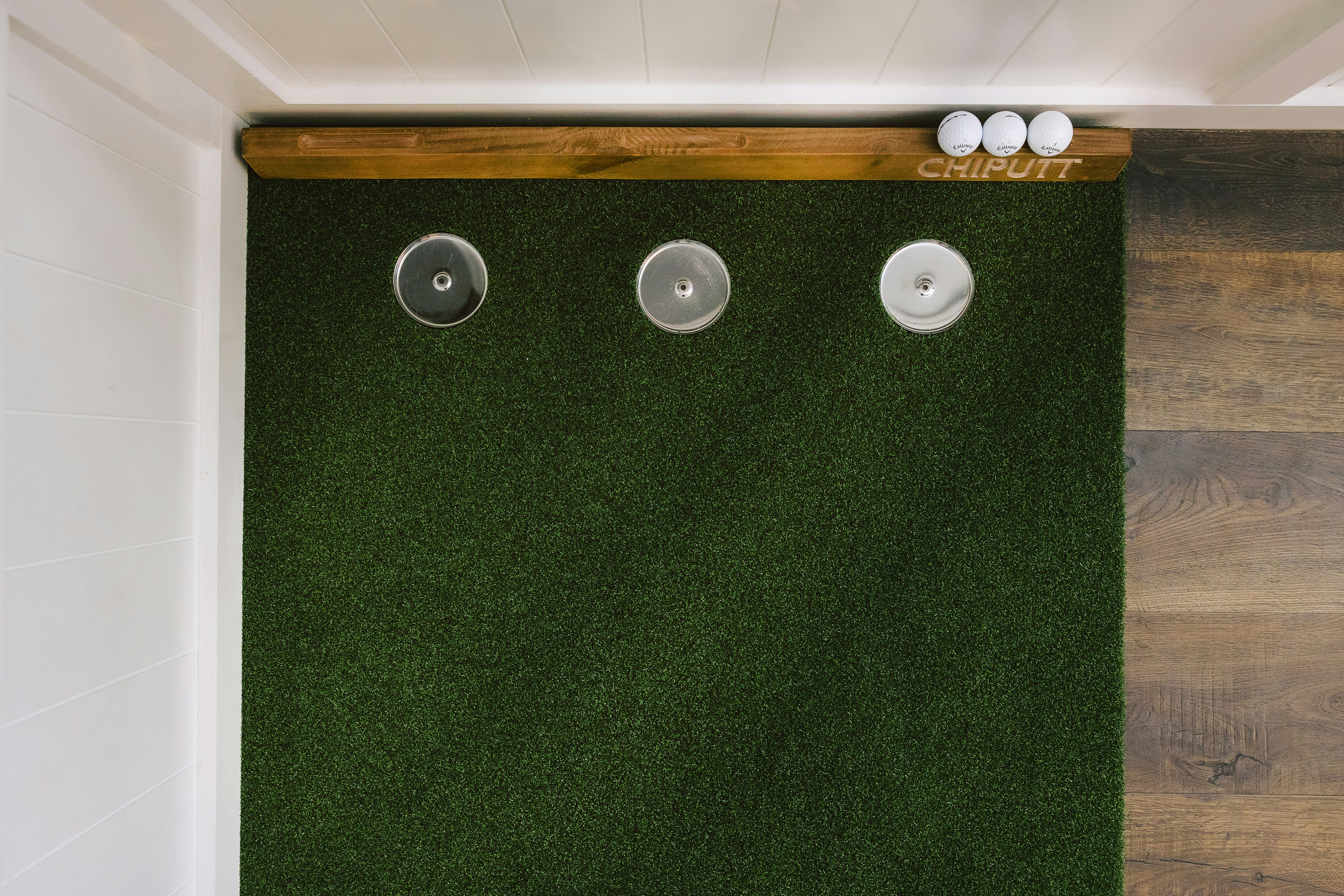 Three golf balls on a putting green with holes.