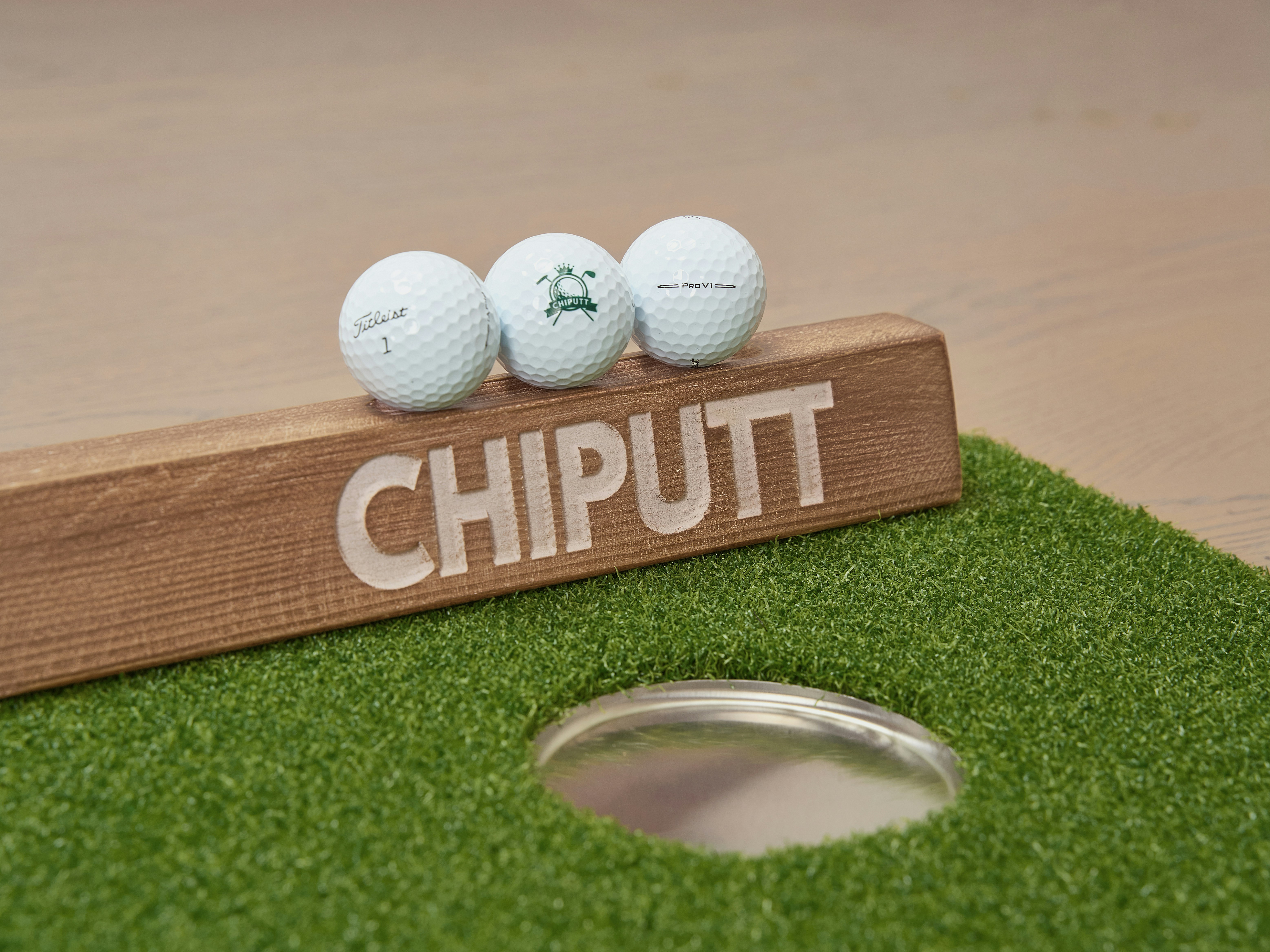 Three golf balls on a chiputt putting surface.