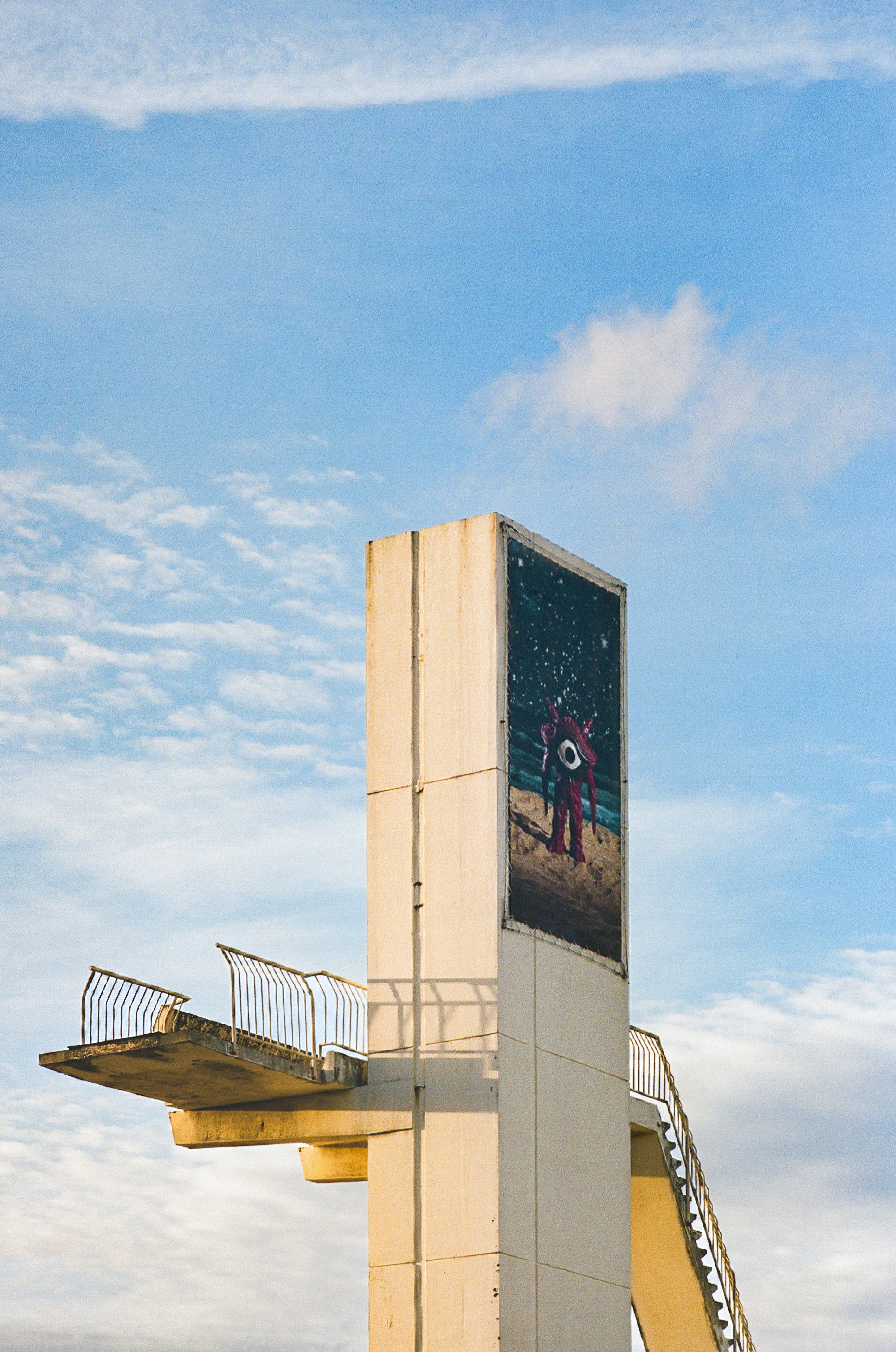 Diving platform with astronaut mural against blue sky