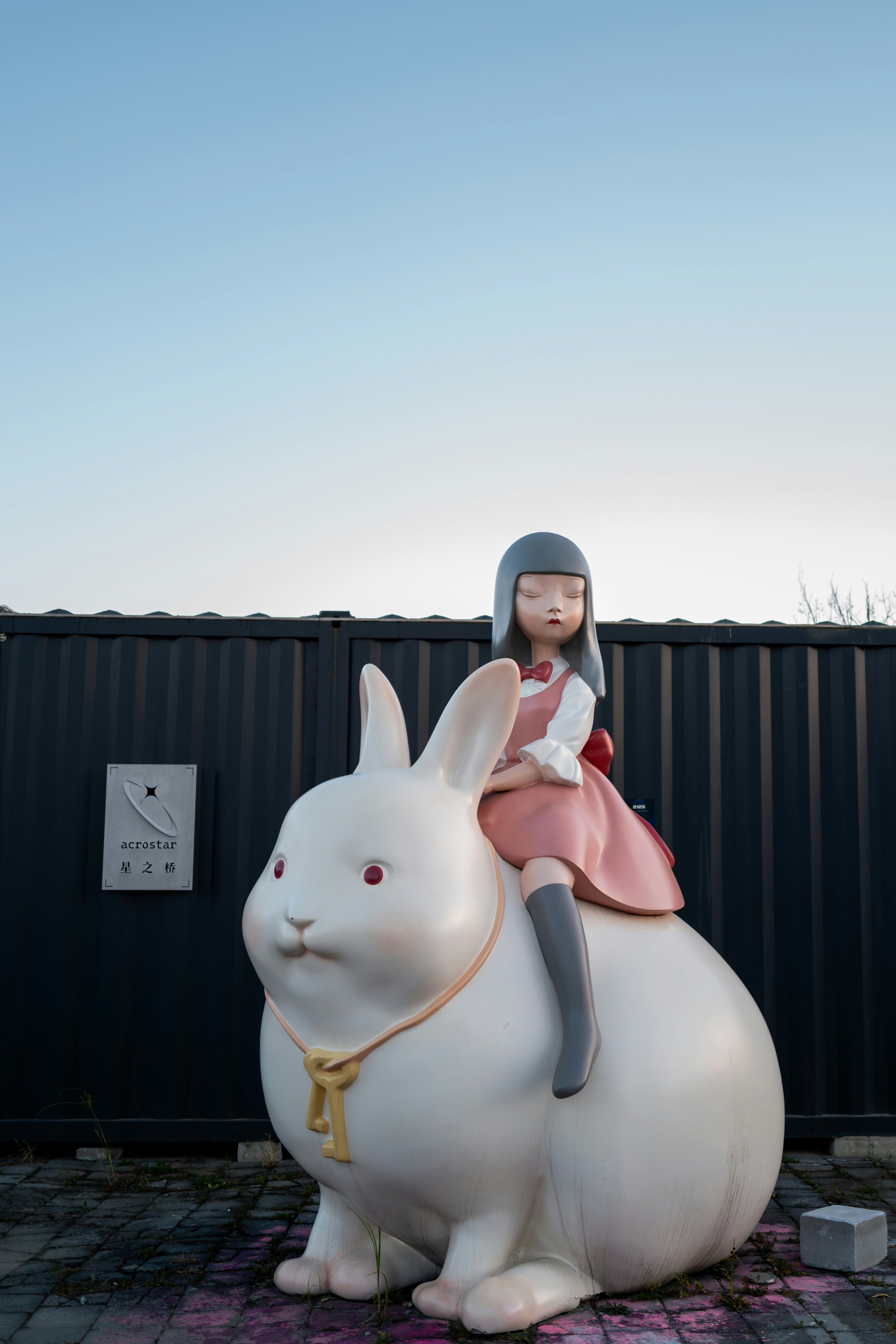 Fille chevauchant une grande sculpture de lapin blanc