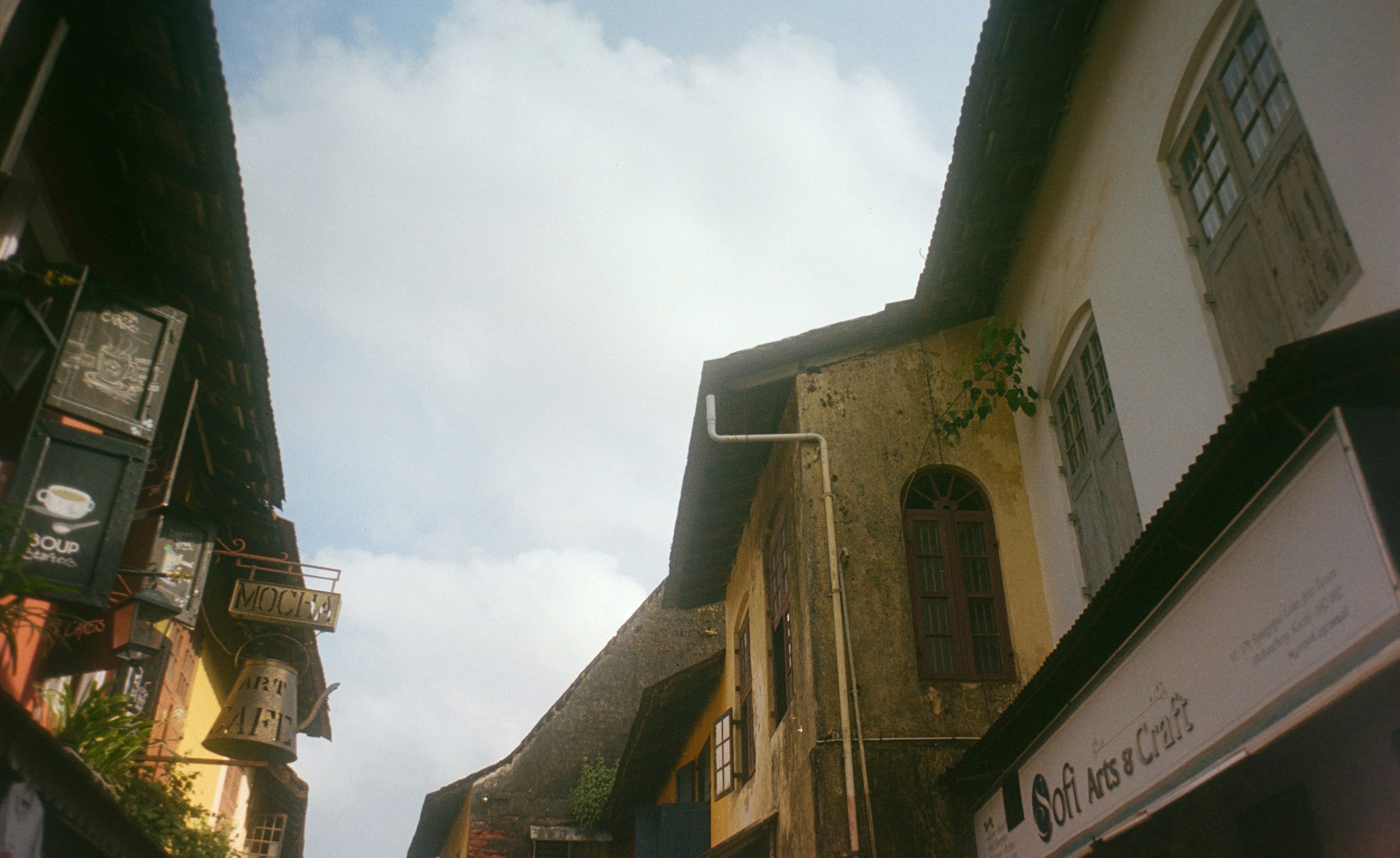 Narrow street with old buildings and cloudy sky.