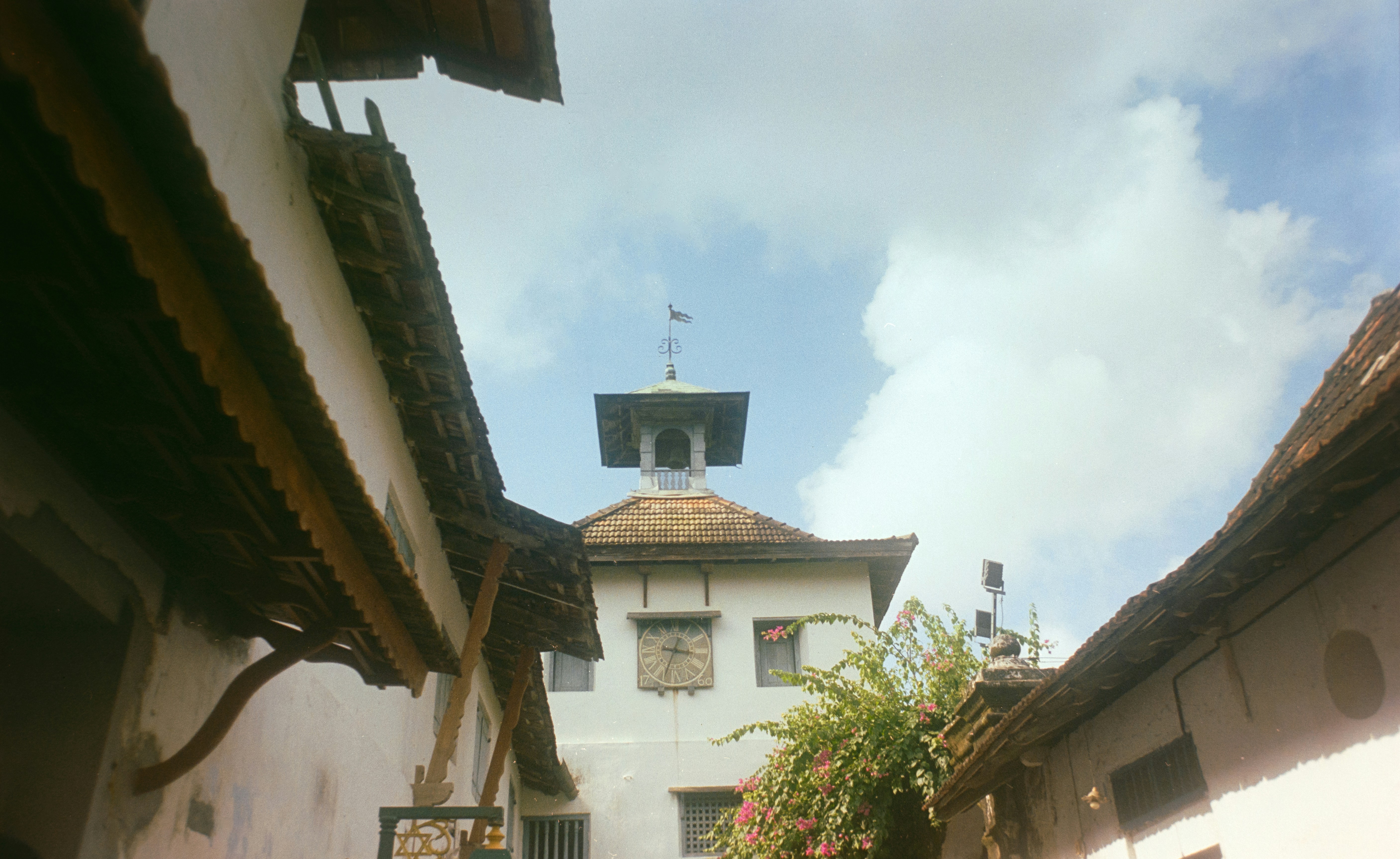 White tower with clock and bell against cloudy sky