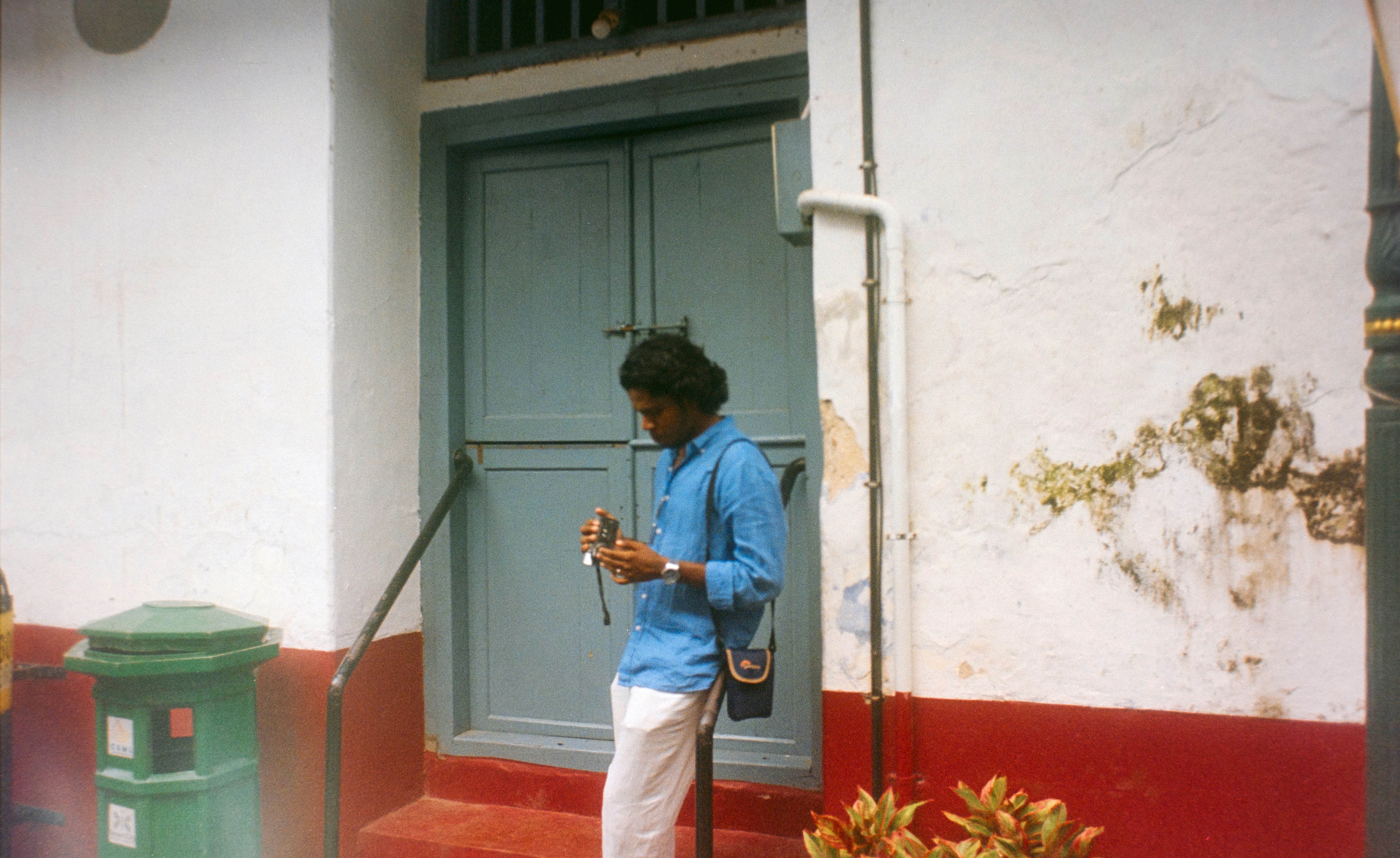 Man in blue shirt standing by a blue door.