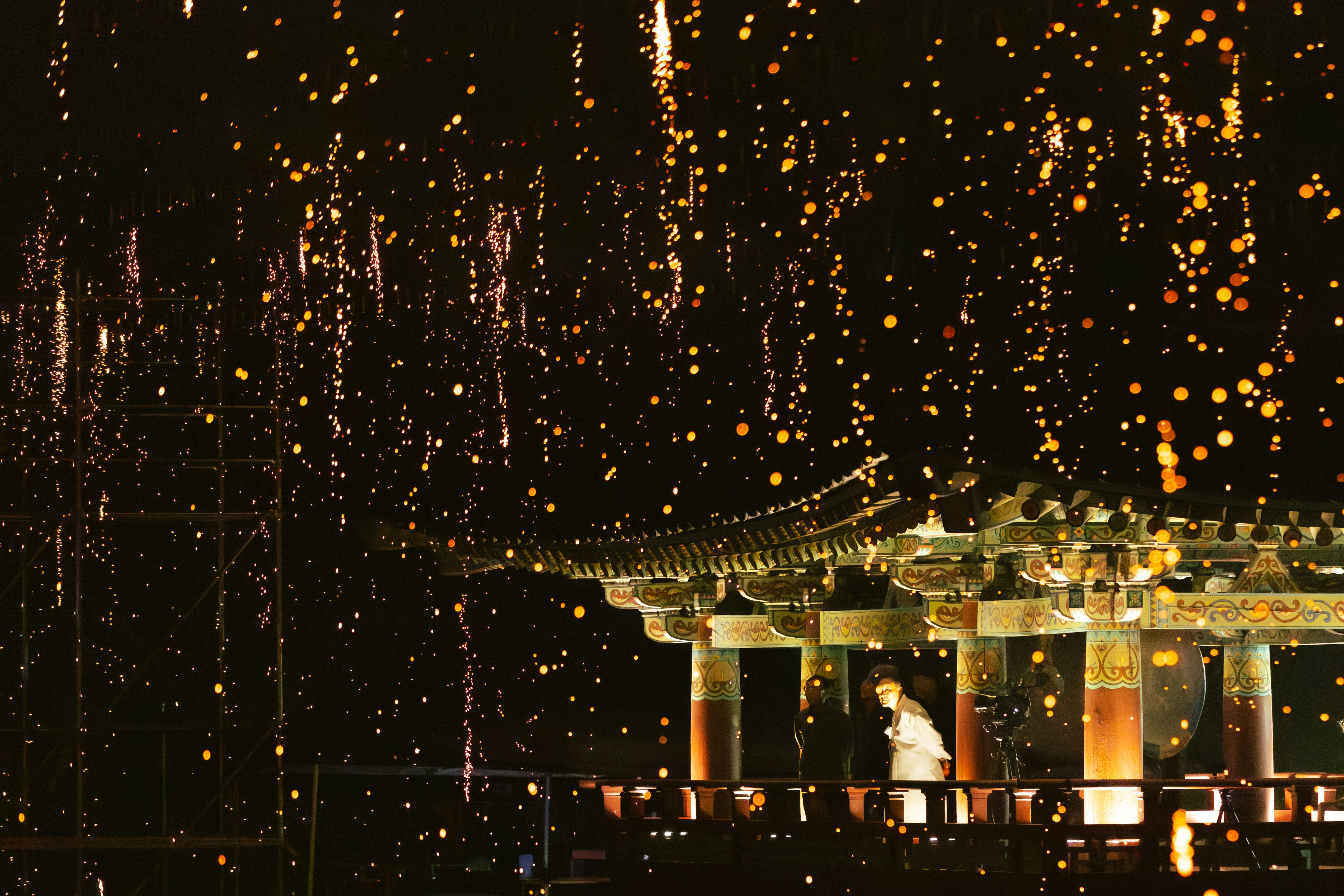 A person stands on a balcony under falling lights